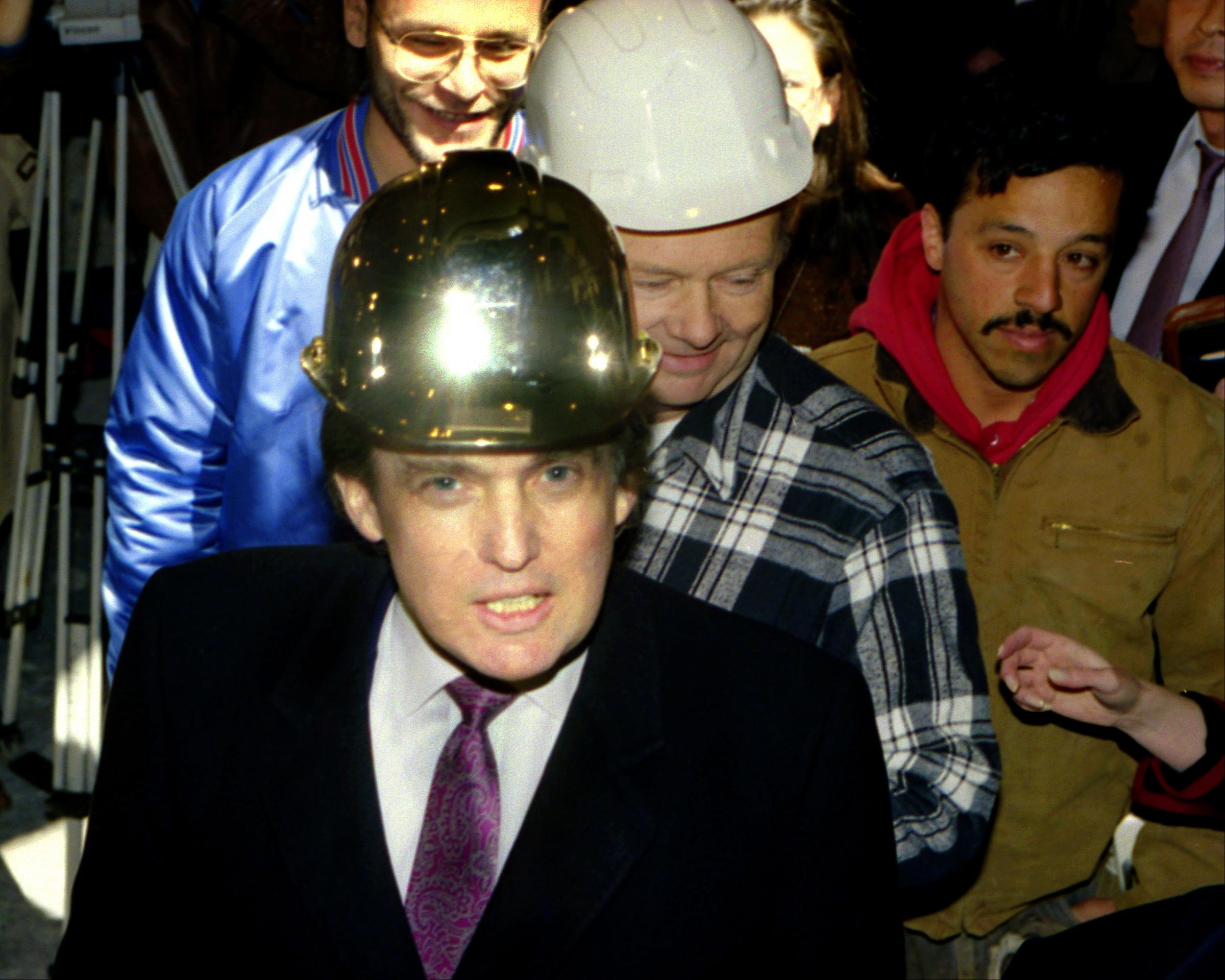 Donald Trump wearing a gold hard hat given to him by construction workers at the Trump Palace.