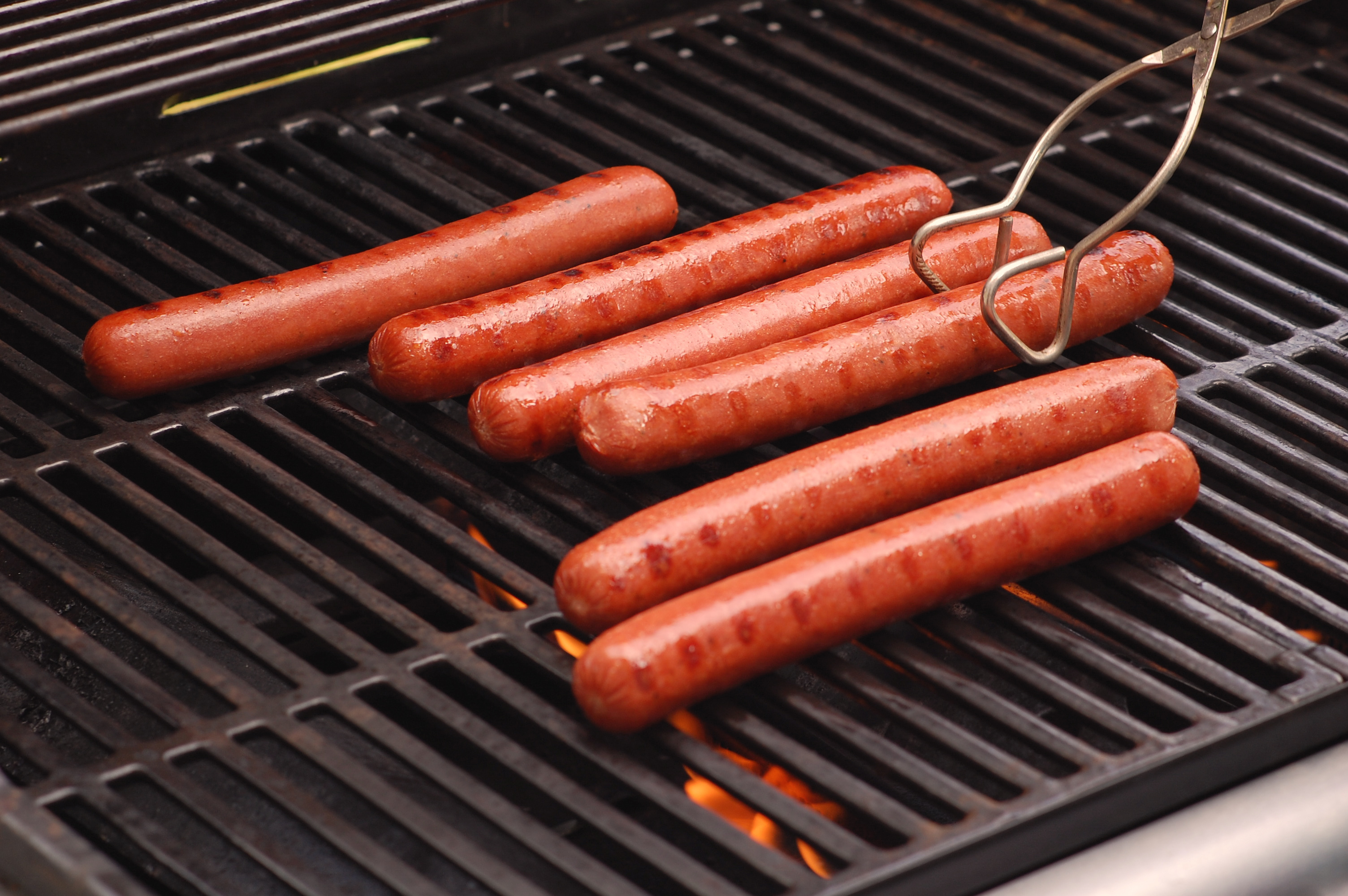 Six hot dogs cooking on a gas-fired barbeque grill. (Matt Carey—Getty Images)