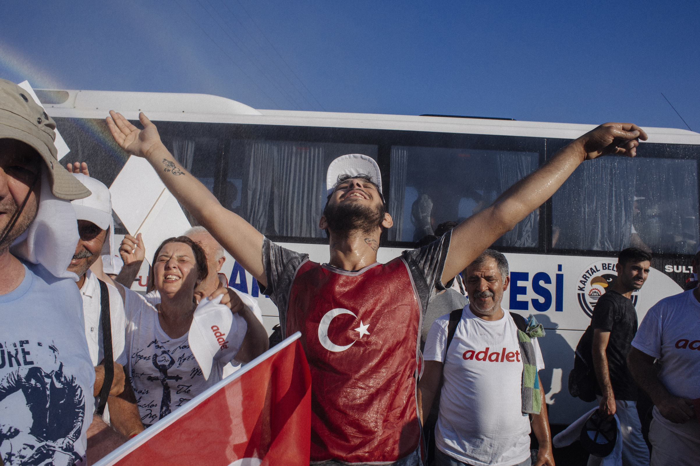 Marchers are cooled by the spray of water in Kartepe, Turkey, July 2, 2017, during  one of the most intense heat waves in a century. On June 15, thousands of people began walking in shifts from Ankara to Istanbul in opposition to the government of President Recep Tayyip Erdogan. Since last year's July 15, 2016 attempted coup, more than 47,000 people have been arrested by the government.
