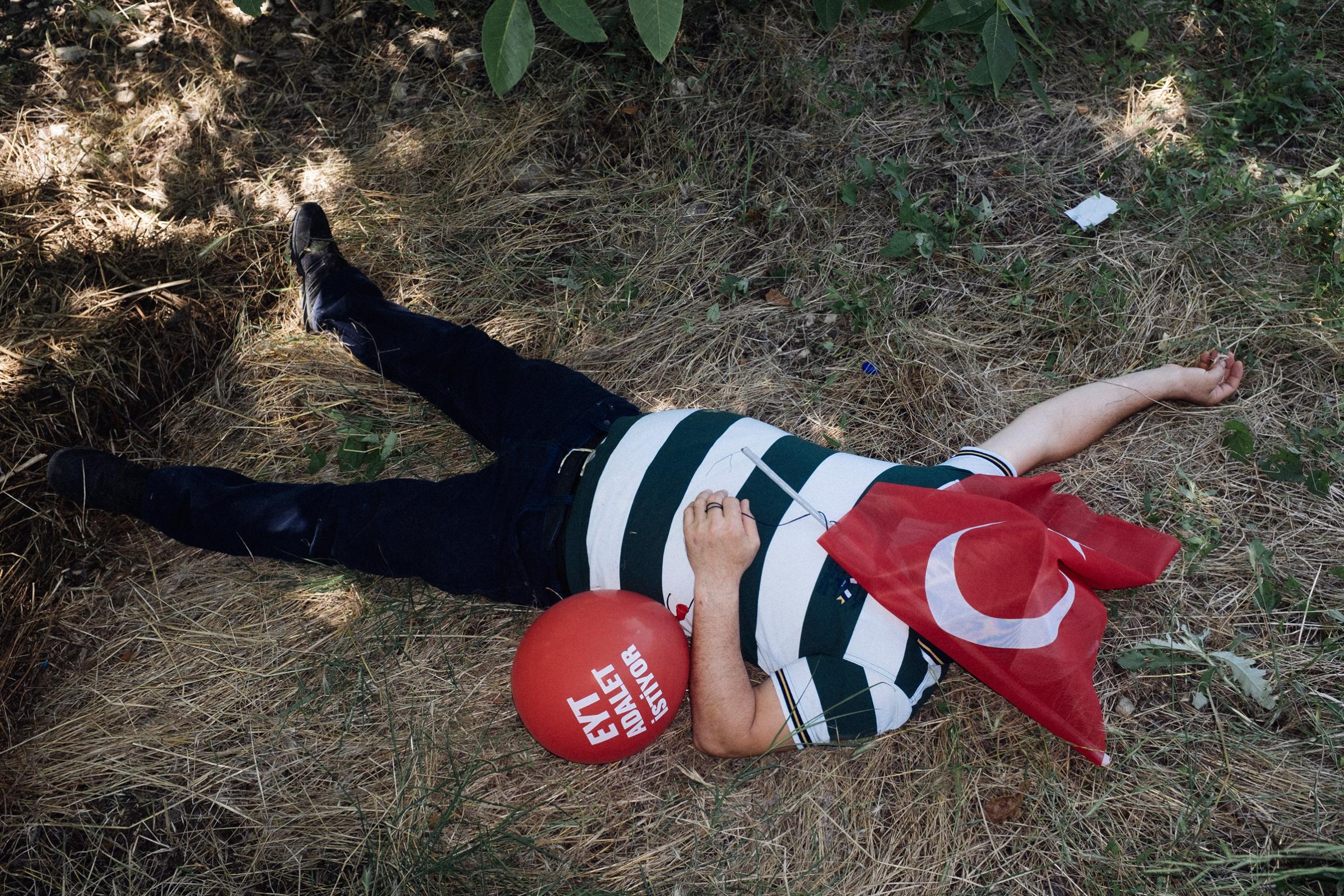 TURKEY, Sakarya, A man sleeps with a Turkish flag on his face, on the field during break time at Justice March. Since last week, Turkey has been suffering one of the most intense heat waves in a century. In this hear, the thousands of people are taking part in shifts in the “justice march” of main opposition Republican People’s Party (CHP) leader Kemal Kilicdaroglu. They are struggling under the burning sun over their head and also the melting asphalt under their feet. 2017