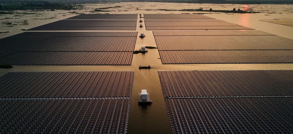Chinese workers ride in a boat through a large floating solar farm project under construction by the Sungrow Power Supply Company on a lake caused by a collapsed and flooded coal mine in Huainan, Anhui province, on June 13, 2017.