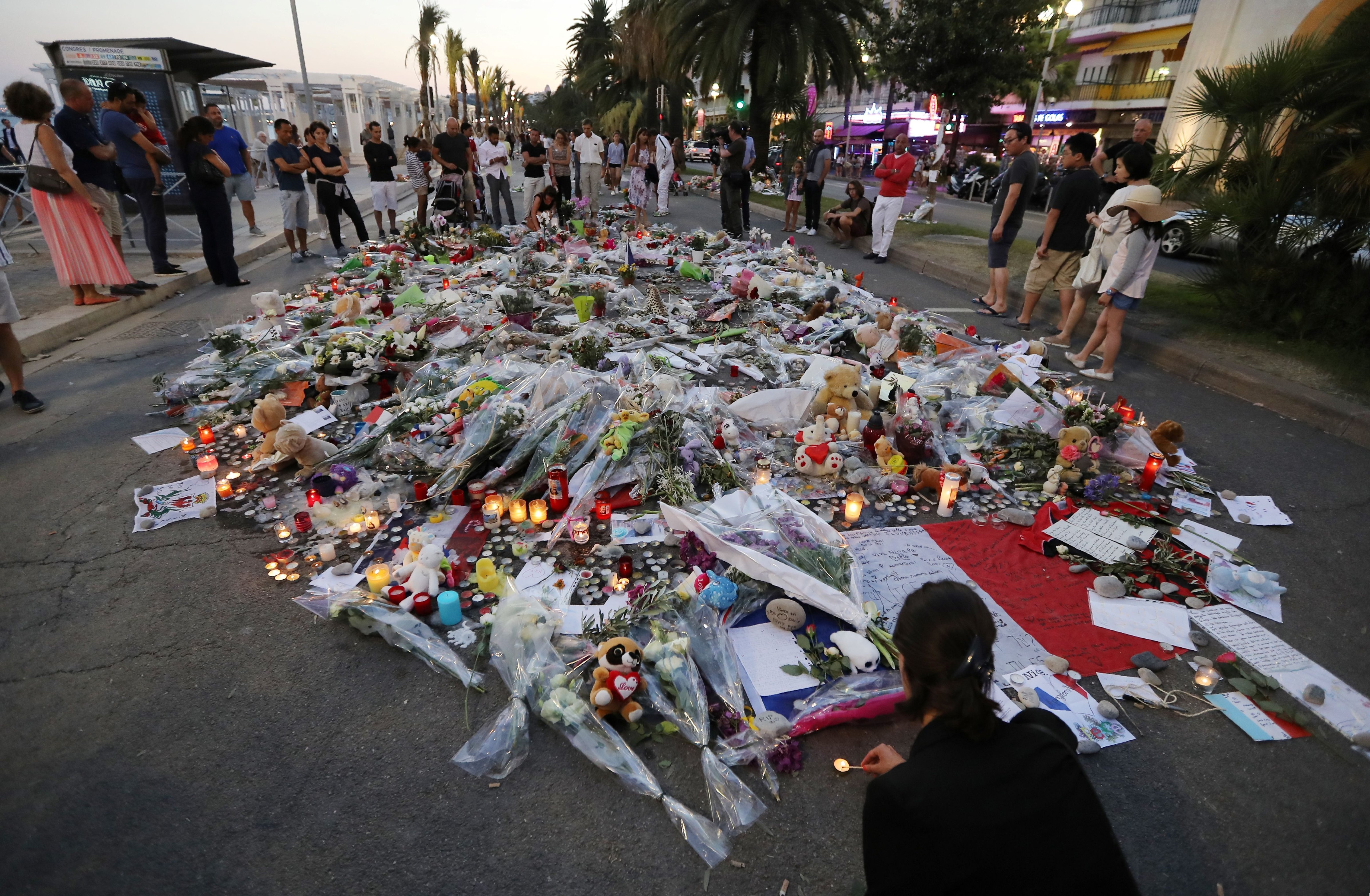 People stand around flowers, candles and messages laid at a makeshift memorial in Nice on July 18, 2016, in tribute to the victims of the deadly attack on the Promenade des Anglais seafront which killed 84 people. (Valery Hache—AFP/Getty Images)