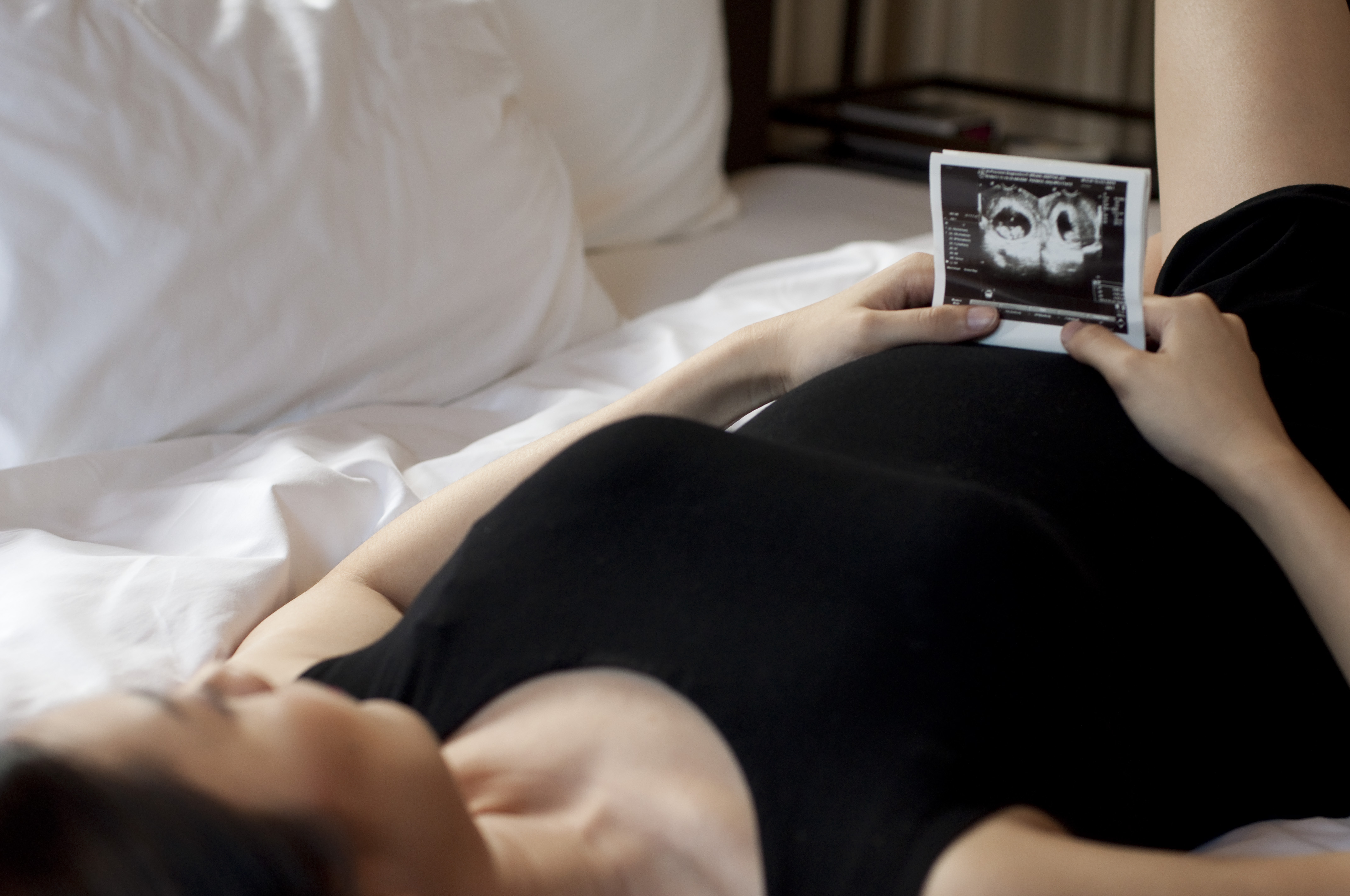 A woman in black dress is holding a sonogram of a baby
