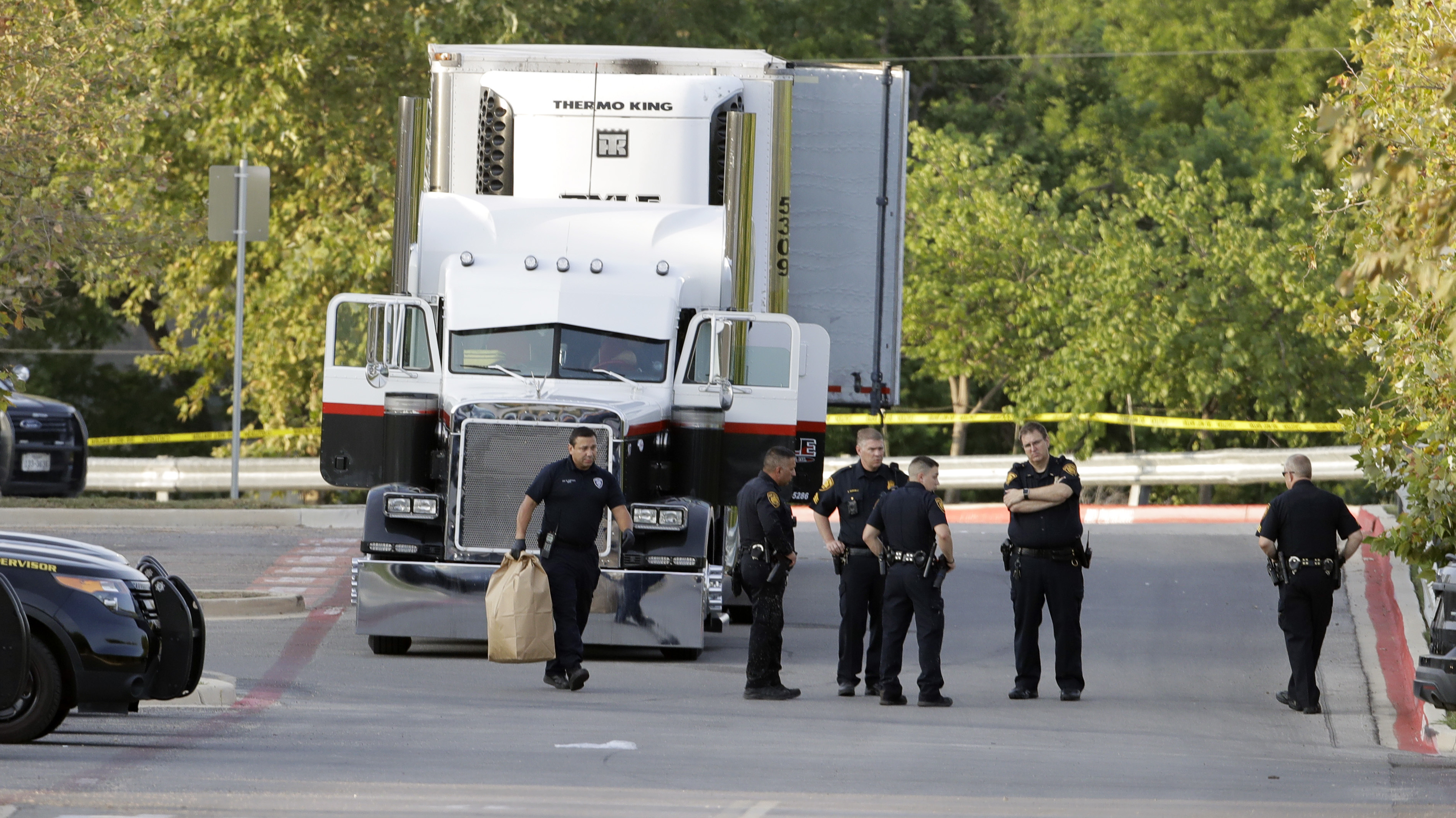 San Antonio police officers investigate the scene Sunday, July 23, 2017, where eight people were found dead in a tractor-trailer loaded with at least 30 others outside a Walmart store in stifling summer heat in what police are calling a horrific human trafficking case, in San Antonio. (Eric Gay&mdash;AP)