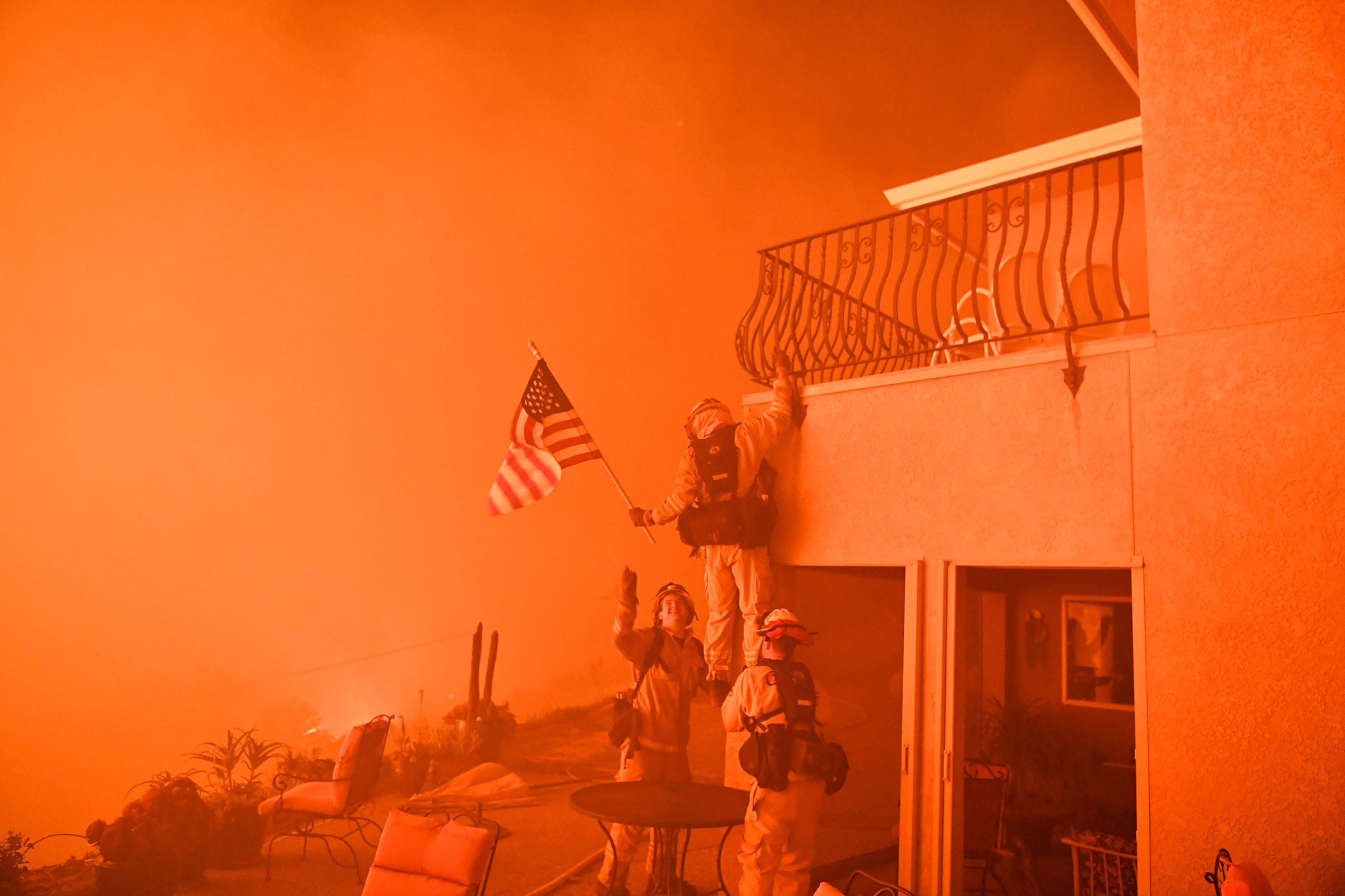Firefighters save an American flag as impending flames from the Wall Fire close in on a luxury home in Oroville, Calif., on July 8, 2017.