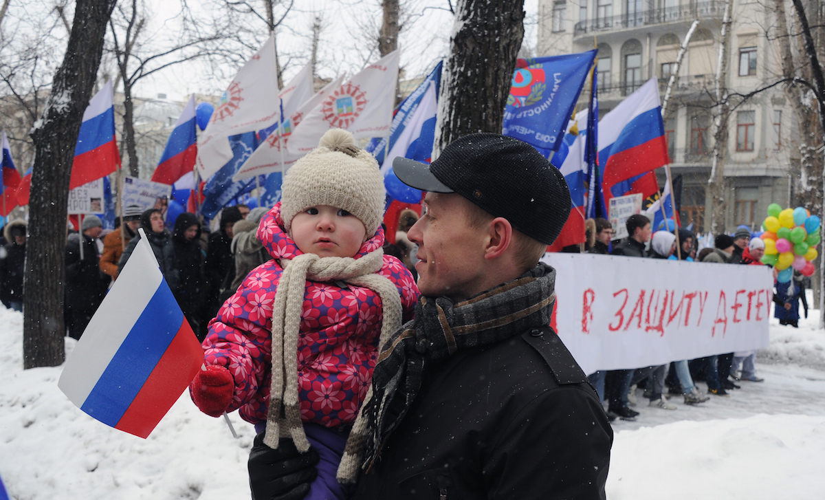 A man walks with his child, as activists from pro-Kremlin children's advocacy groups march through Moscow on March 2, 2013 to call on authorities to ban all foreign adoptions. The banner reads "The March for Protection of the Children." (Alexander Nemenov—AFP/Getty Images)
