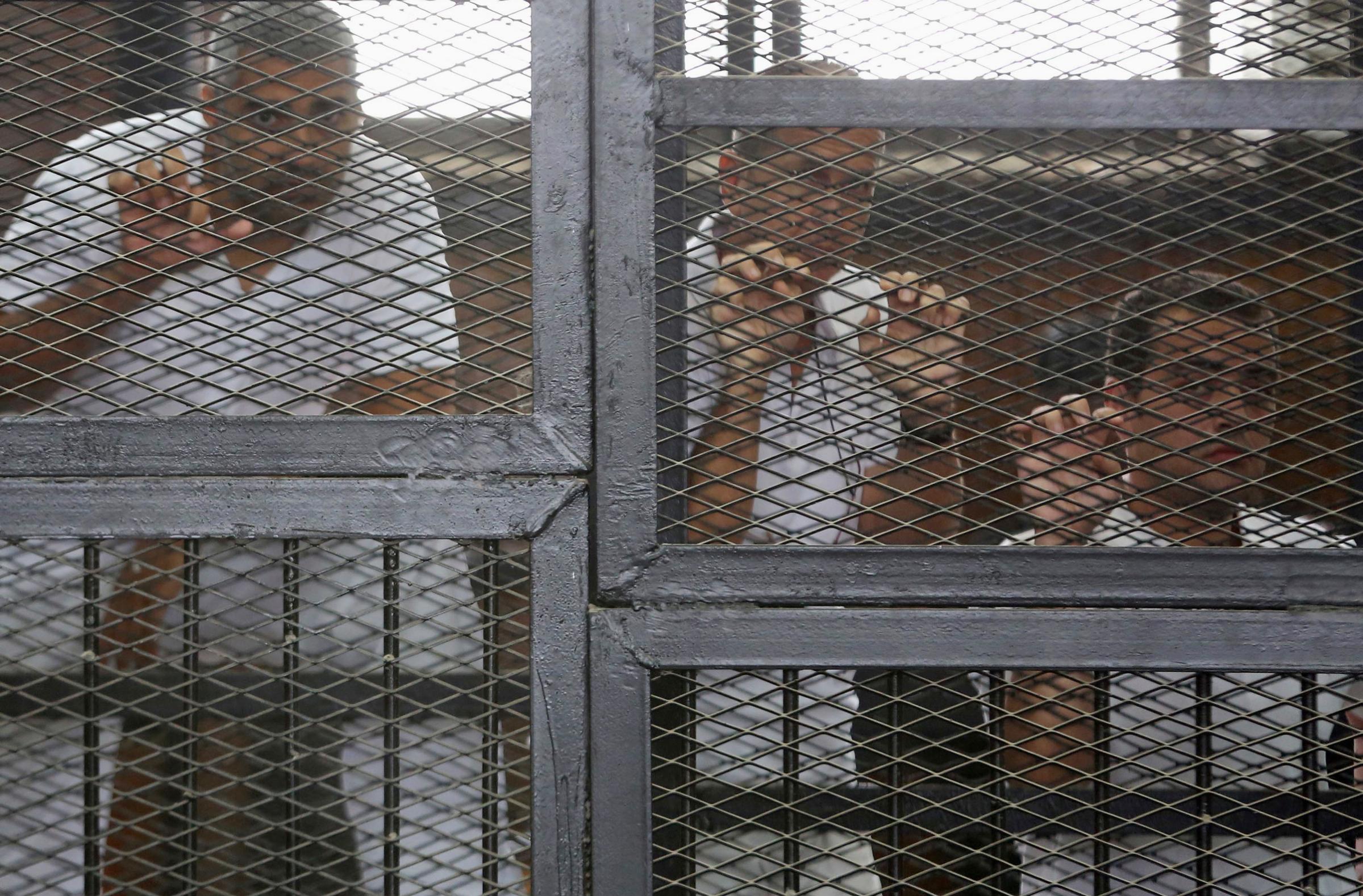 Al Jazeera journalists Mohammed Fahmy, Peter Greste and Baher Mohamed behind bars at a court in Cairo on May 15, 2014.