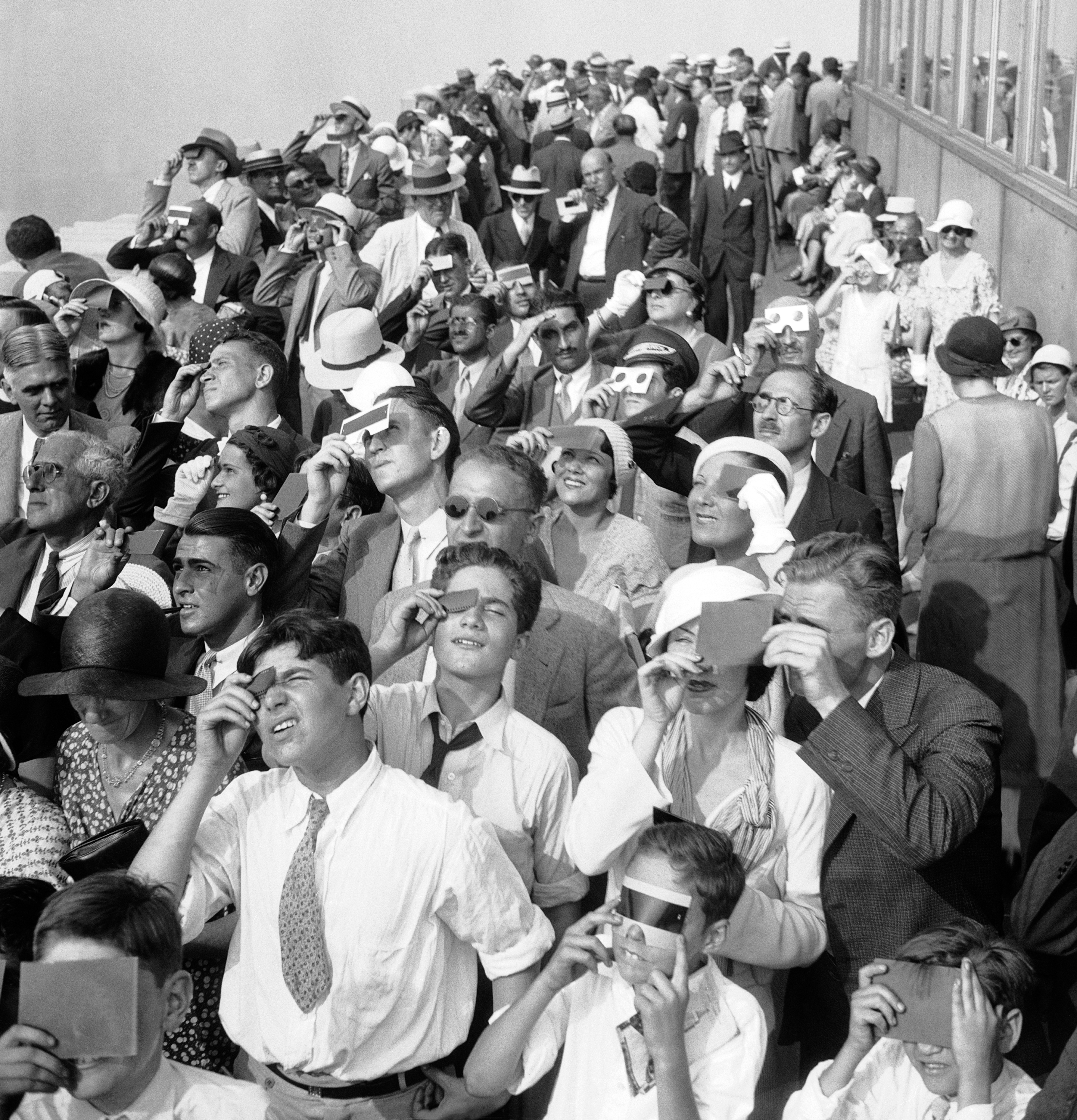 Eclipse watchers squint through protective film as they view a partial eclipse of the sun from the top deck of New York's Empire State Building Aug. 31, 1932. (AP)
