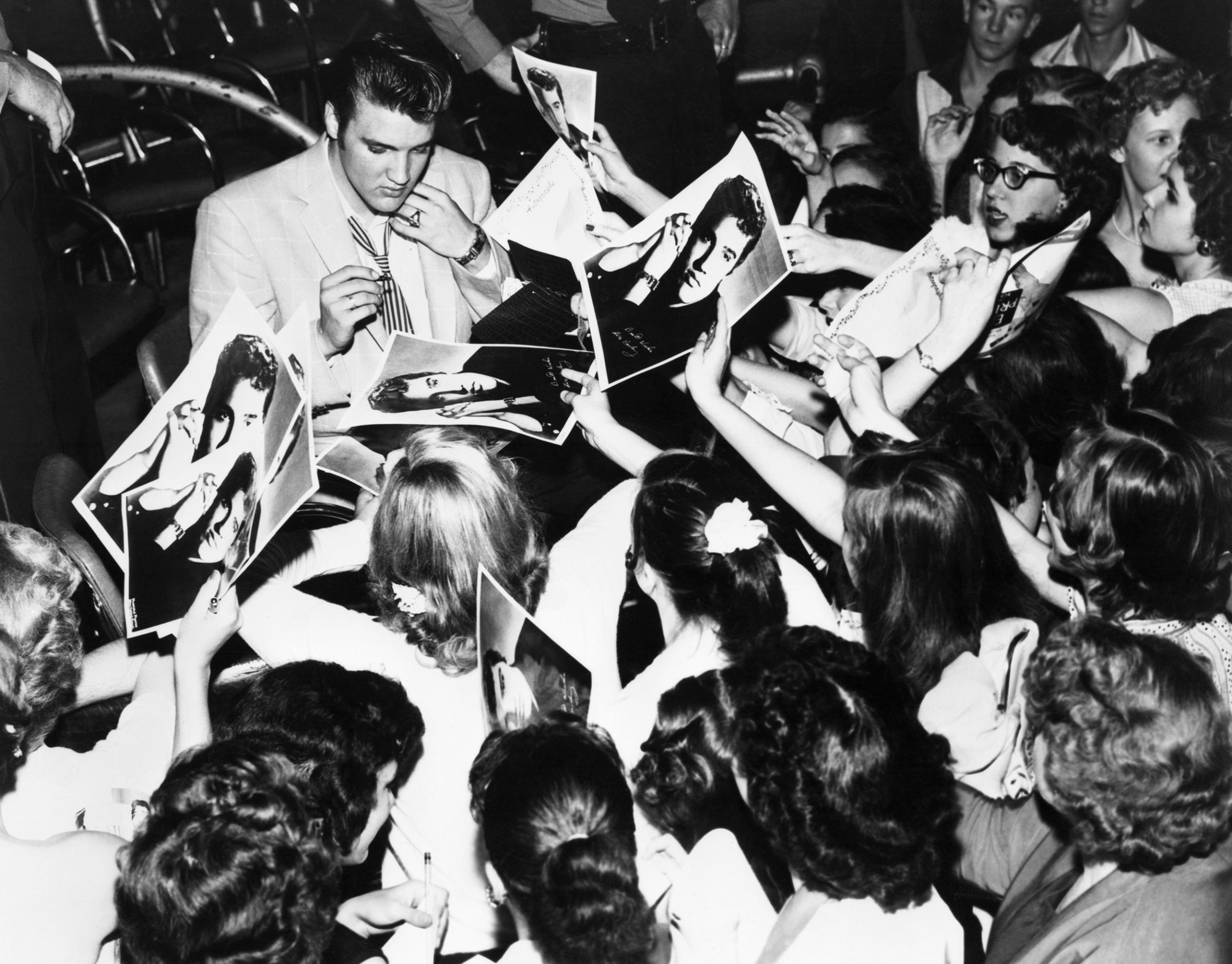 Elvis is surrounded by his enthusiastic teenage fans in Houston, TX., 1956.