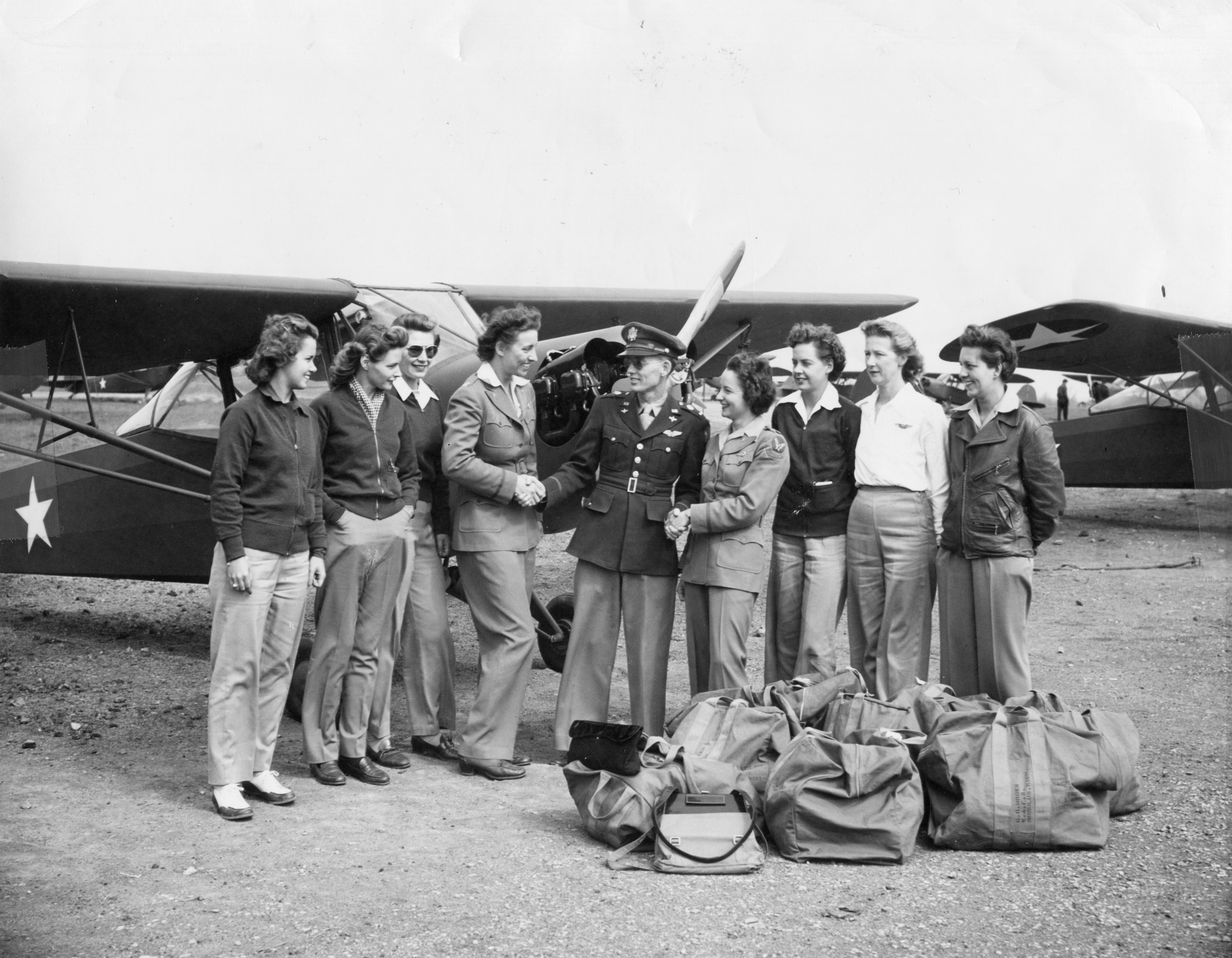 American military commander Lt. George Fairfield (center) shakes hands with Women's Air Force Service Pilot (WASP), and former Olympic swimming champion, Katherine Rawls Thompson (fourth left), and another unidentified pilot, as they are watched by six additional WASPs, all of whom had flown L-2 'Grasshopper' liaison planes to various Army bases from the Taylorcraft factory, Alliance, Ohio, in June 1943. (PhotoQuest—Getty Images)