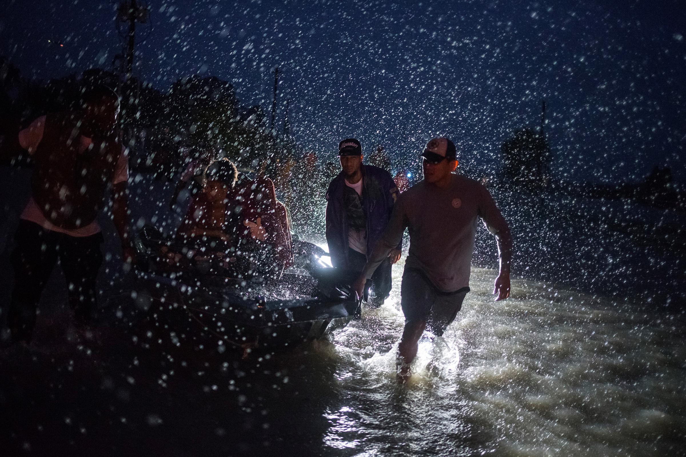 Samaritans help push a boat with evacuees to high ground during a rain storm caused by Tropical Storm Harvey along Tidwell Road in east Houston