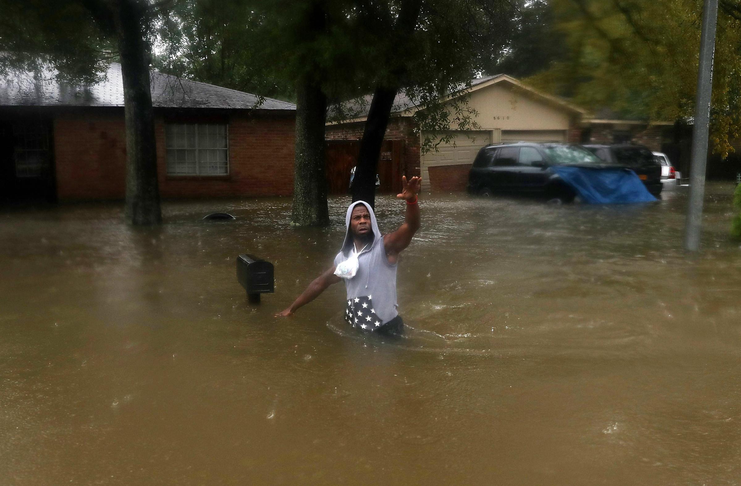 A person waves to rescuers as he walks through a flooded street after the area was inundated with flooding from Hurricane Harvey on Aug. 28, 2017 in Houston.