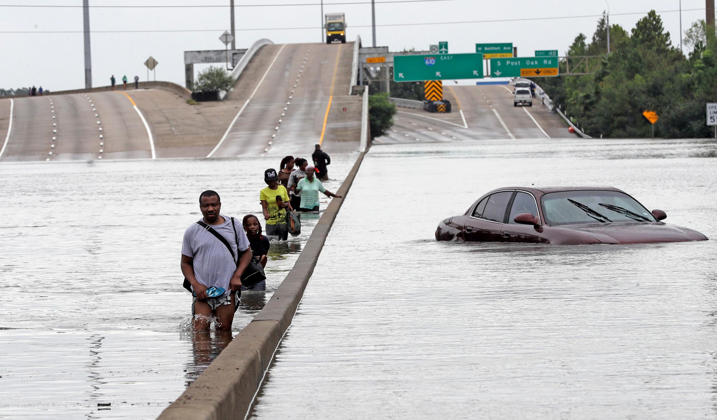 Evacuees wade down a flooded section of Interstate 610 as floodwaters from Tropical Storm Harvey rise, Aug. 27, 2017, in Houston.