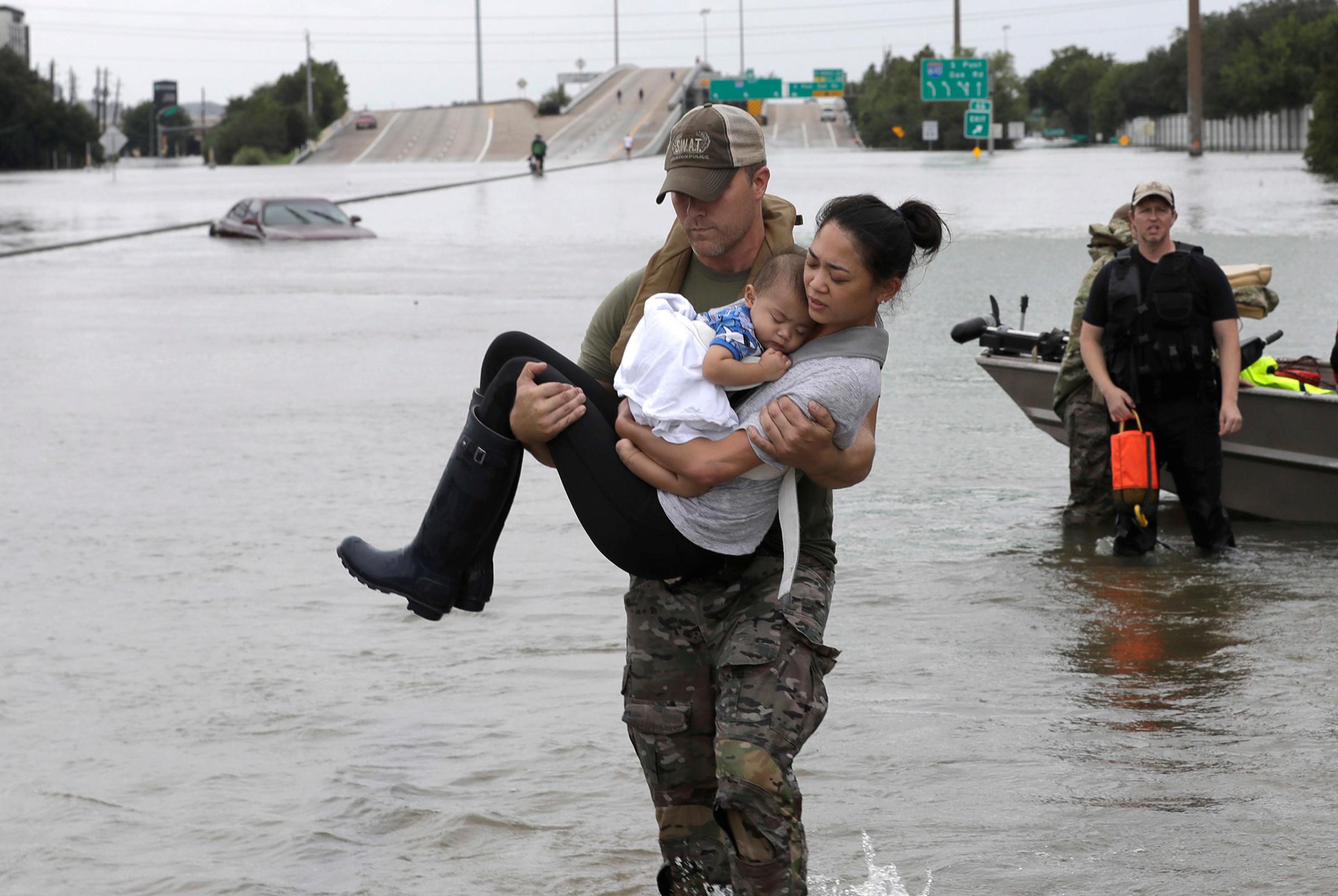Houston Police SWAT officer Daryl Hudeck carries Catherine Pham and her 13-month-old son Aiden after rescuing them from their home surrounded by floodwaters from Tropical Storm Harvey in Houston, on Aug. 27, 2017.