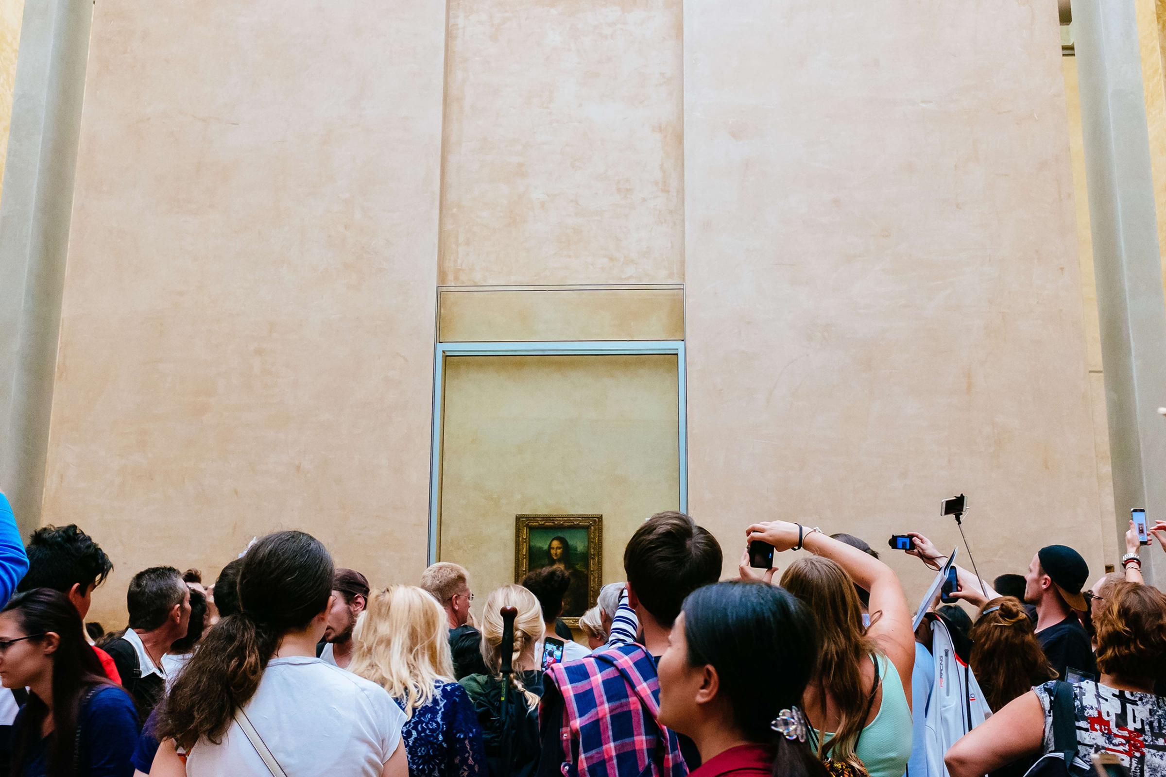Mona Lisa painting surrounded by hundreds of visitors in the