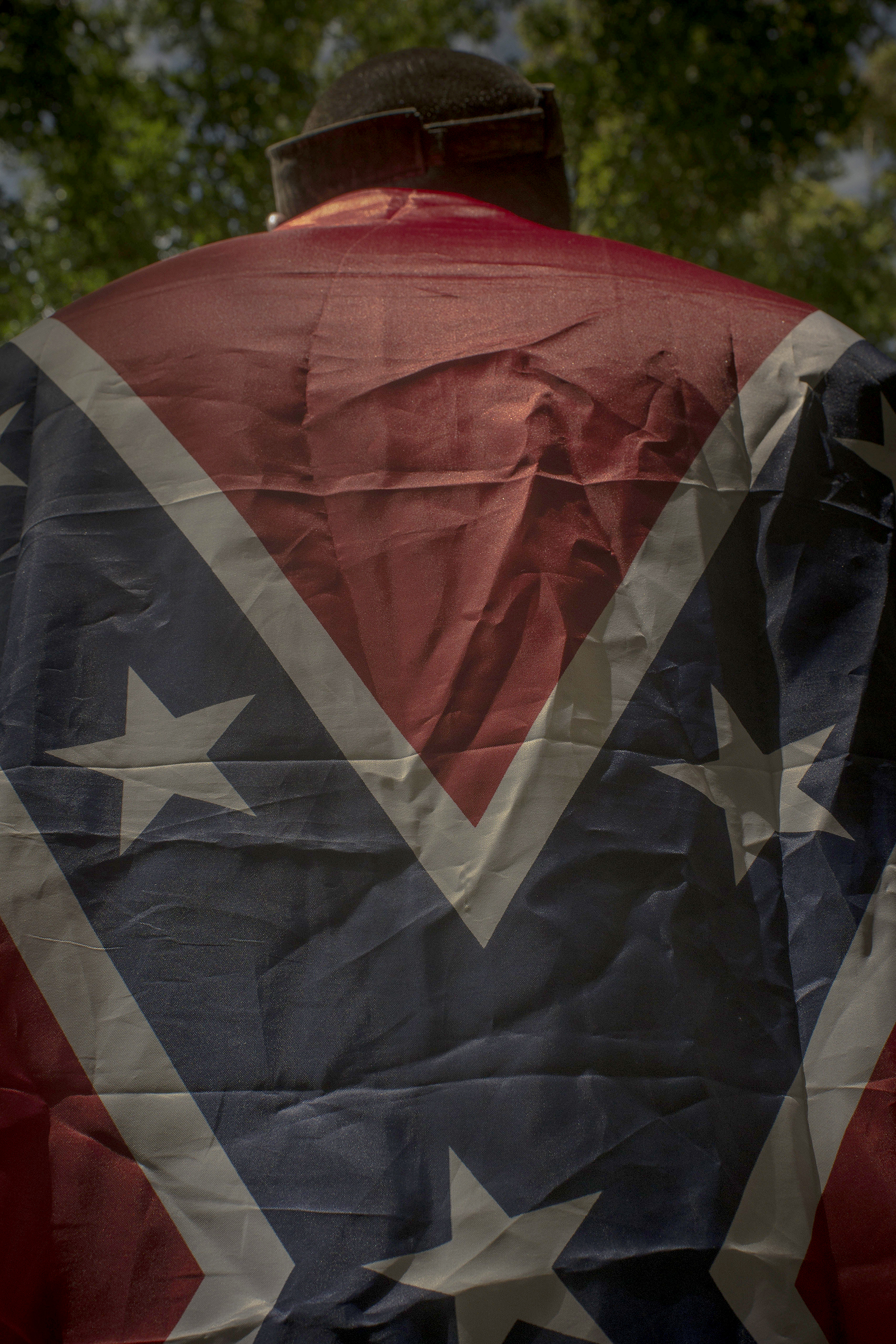 A Unite the Right protester drapes himself in a Confederate flag during a KKK rally in Charlottesville, Va., on July 8, 2017.