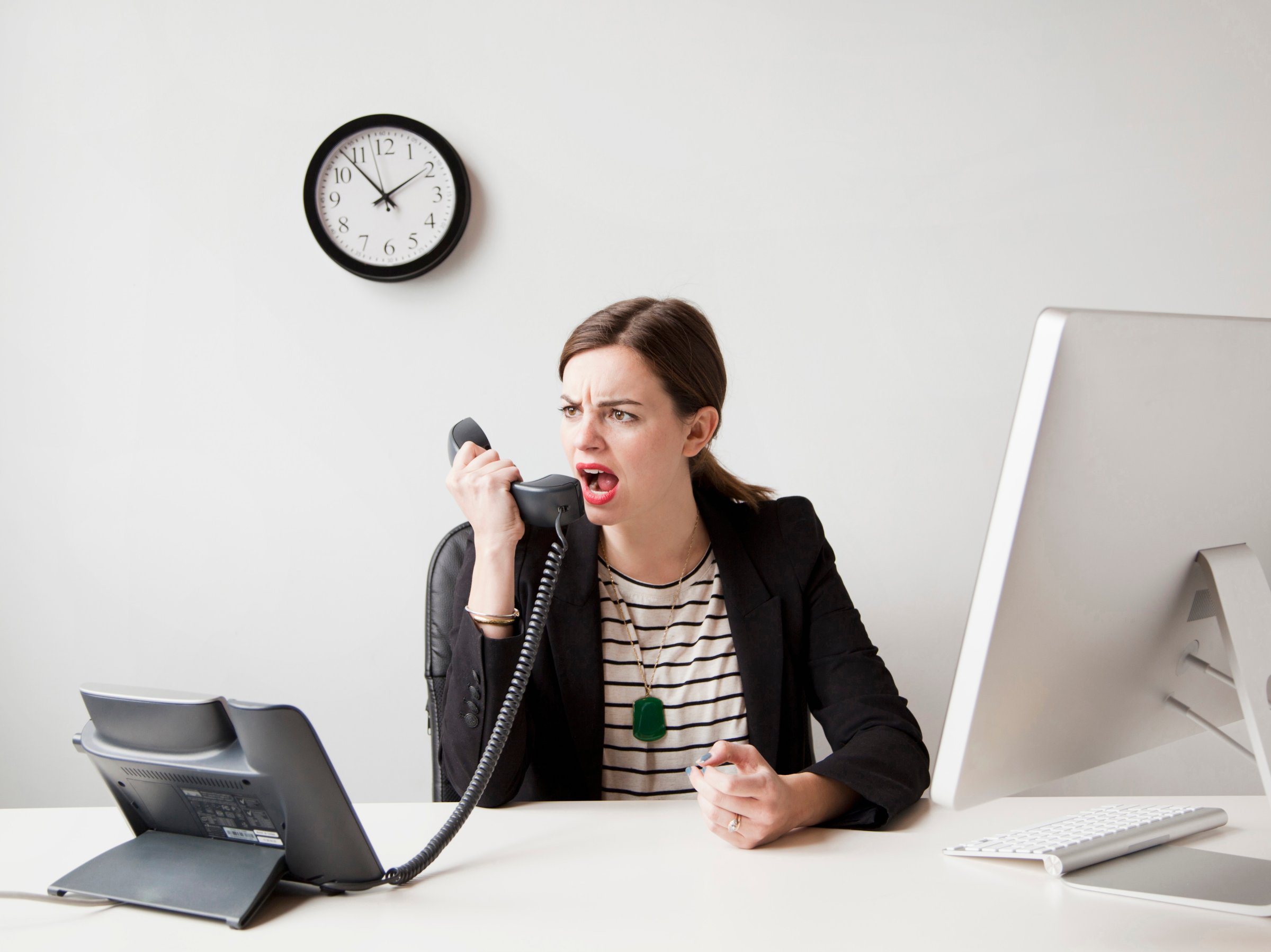 Studio shot of young woman working in office yelling into phone