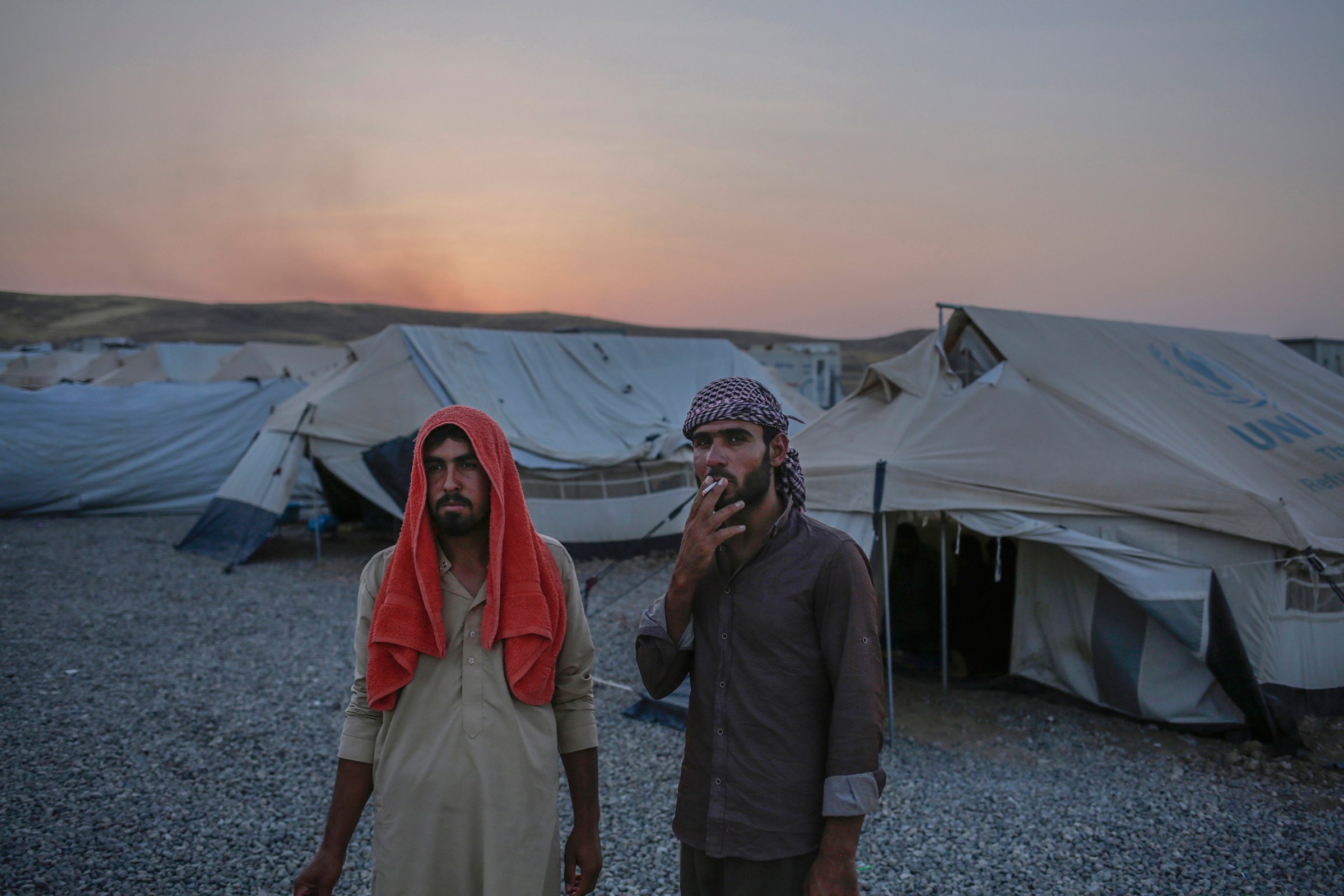 Younes Abdullah, left, and his nephew Rakan Hamid Jasim stand inside the Chamakor camp for displaced people in Northern Iraq. They both want to return to their homes in the town of Zummar, currently under Kurdish control, but Kurdish security forces don't allow them to return. The two relatives lived under Islamic State rule for almost three years.