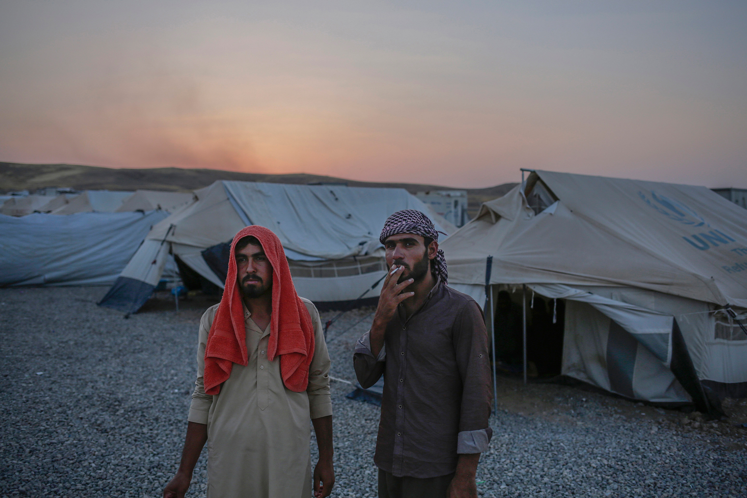 Younes Abdullah, left, and his nephew Rakan Hamid Jasim stand inside the Chamakor camp for displaced people in Northern Iraq. They both want to return to their homes in the town of Zummar, currently under Kurdish control, but Kurdish security forces don't allow them to return. The two relatives lived under Islamic State rule for almost three years. (Bram Janssen—AP)