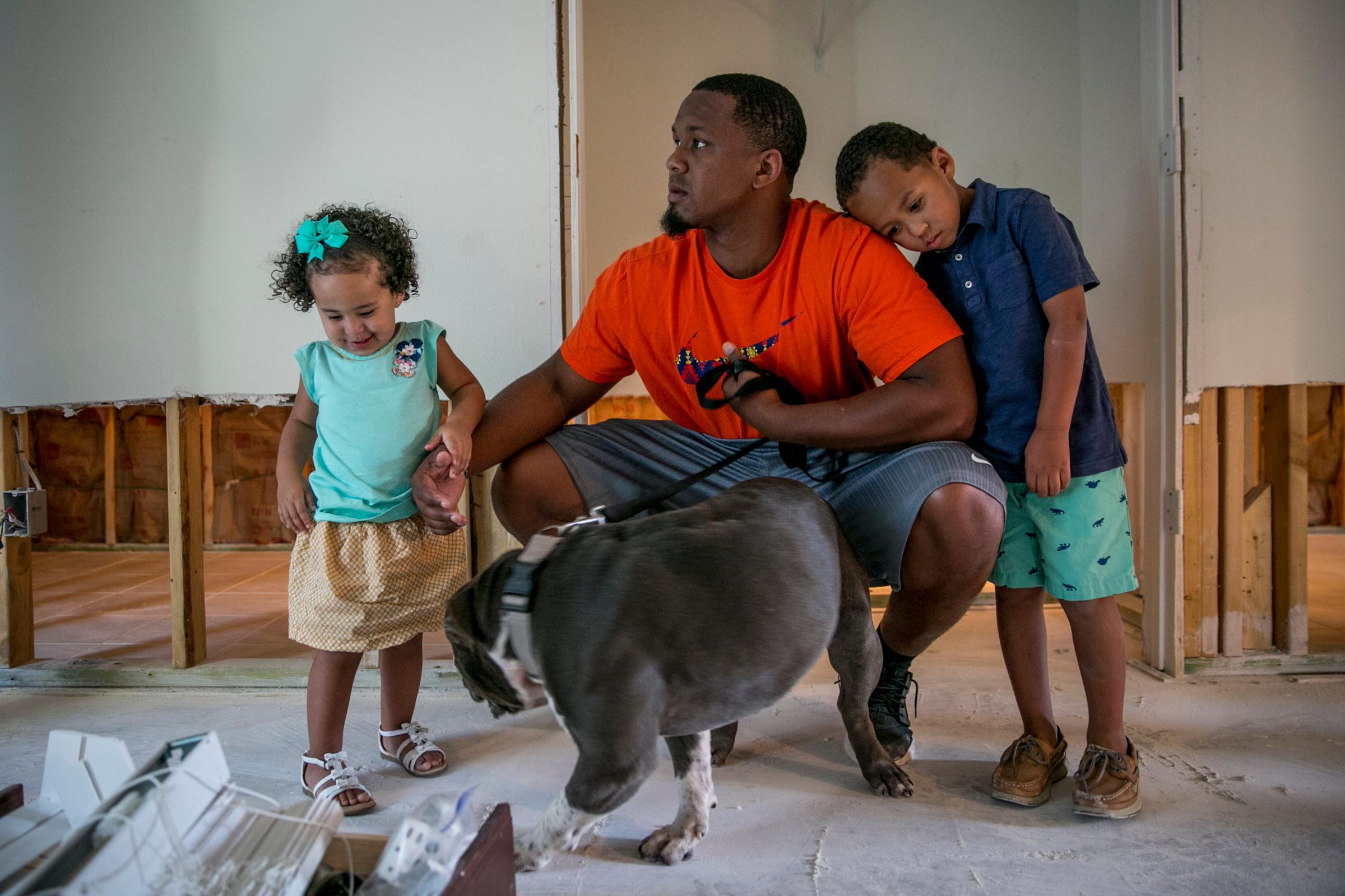 HOUSTON, TEXAS - September 12, 2017: Aubree, 1; Bruce the dog; Isiah, 28; and Bryson, 4, inside their home. The Courtney family's home in the Hunterwood neighborhood of Houston flooded during Hurricane Harvey.  CREDIT: Ilana Panich-Linsman for TIME