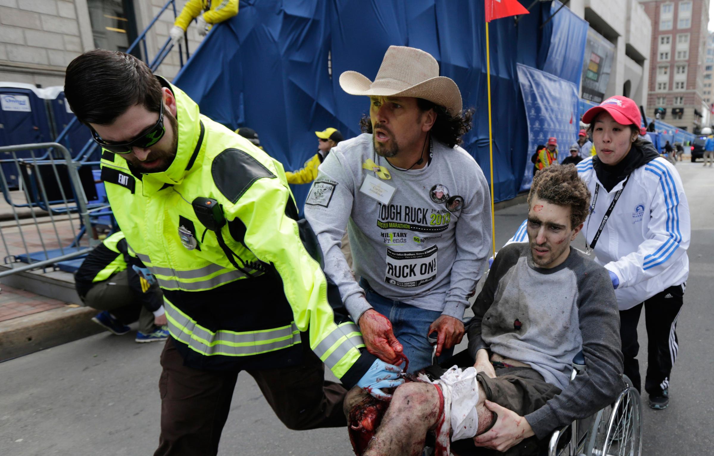 Jeff Bauman is helped by Emergency Medical Services EMT Paul Mitchell, left, Carlos Arredondo, center, and Devin Wang, right, after he was injured in one of two explosions near the finish line of the Boston Marathon on April 15, 2013.