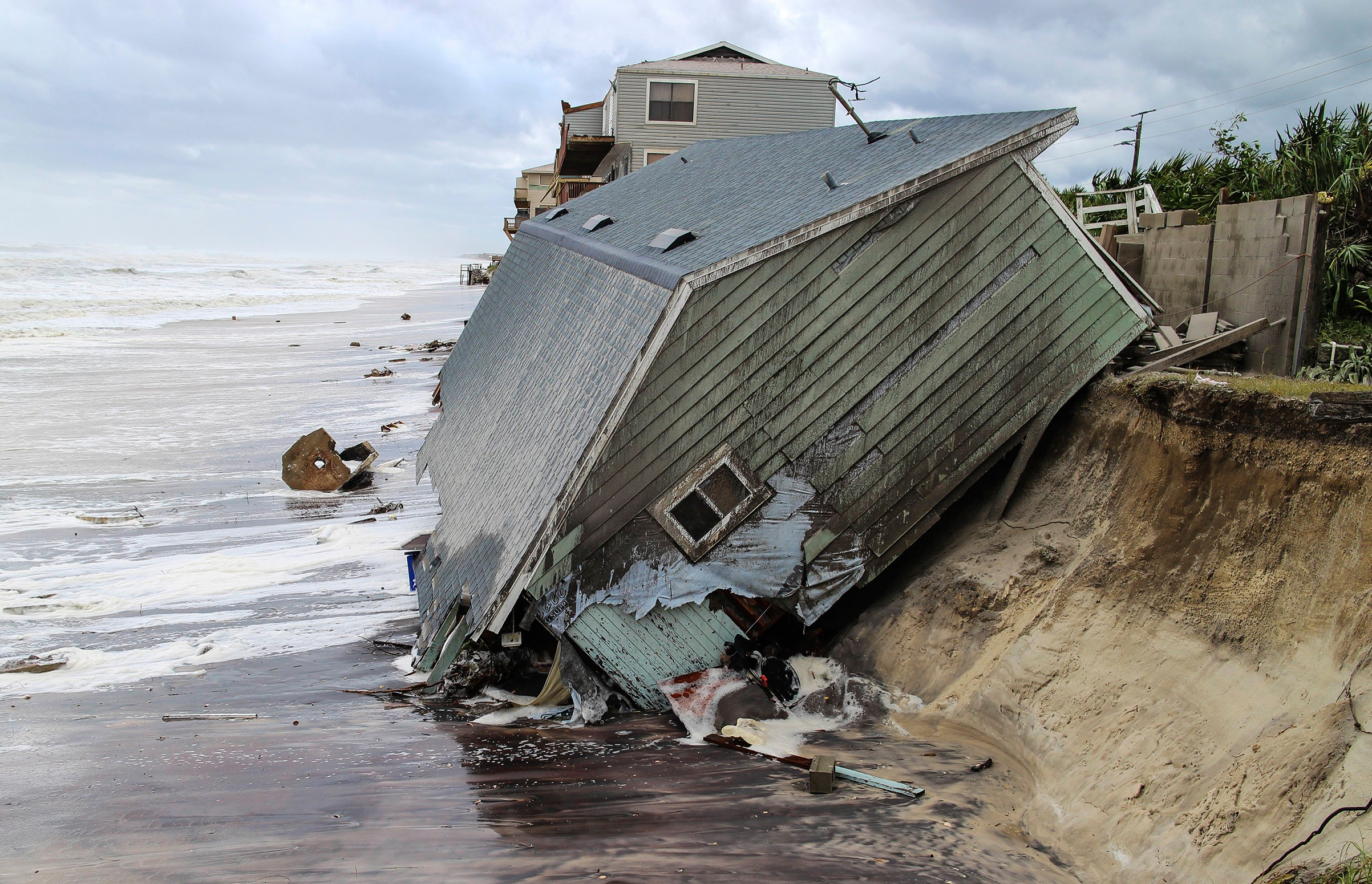 A house slides into the ocean on the Atlantic Coast—one more home built too close to danger (Gary Lloyd McCullough—The Florida Times-Union/AP)