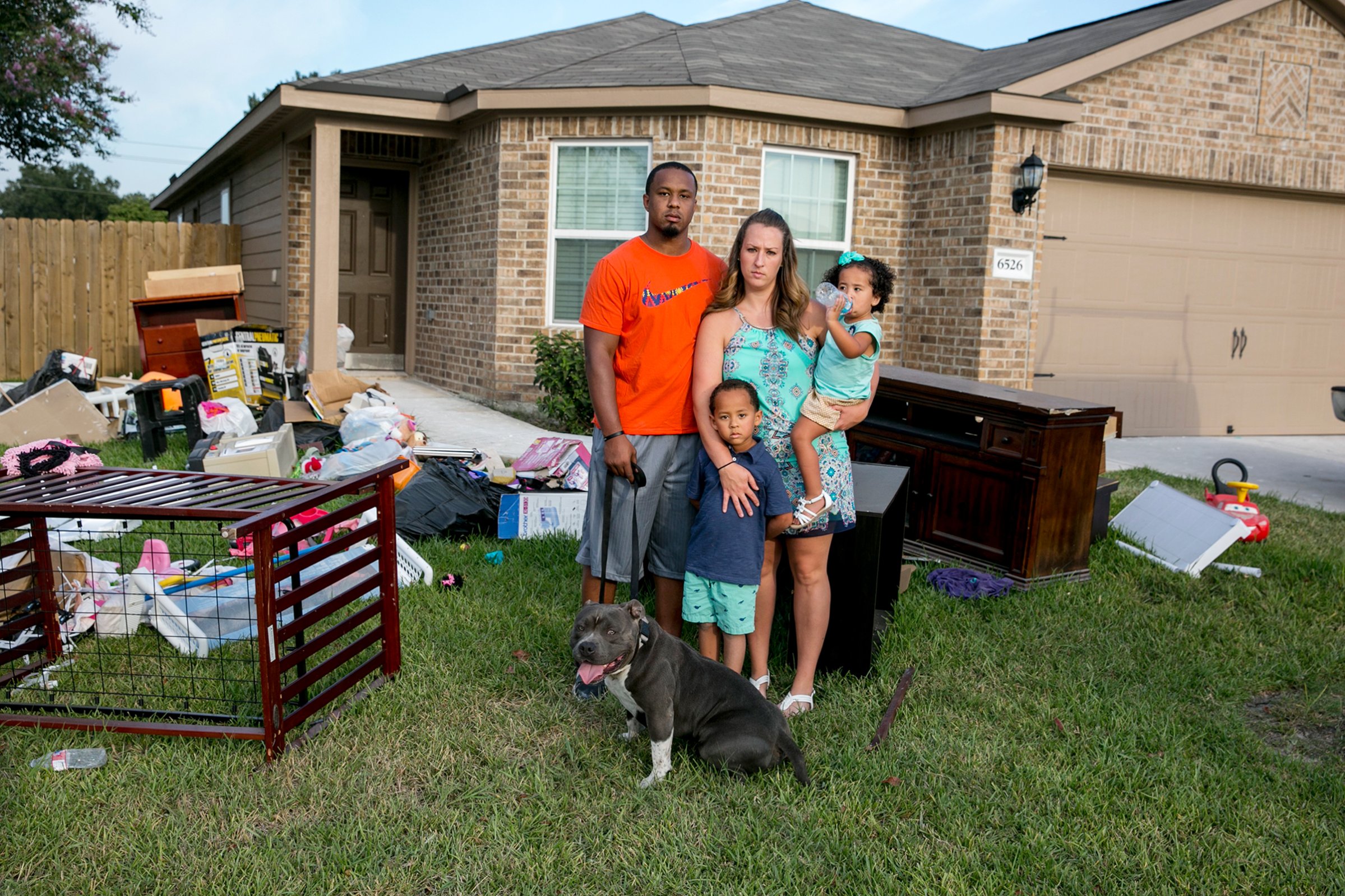 Isiah Courtney stands in the front yard of his Houston home with his wife, Danielle, son Bryson, daughter Aubree and dog Bruce