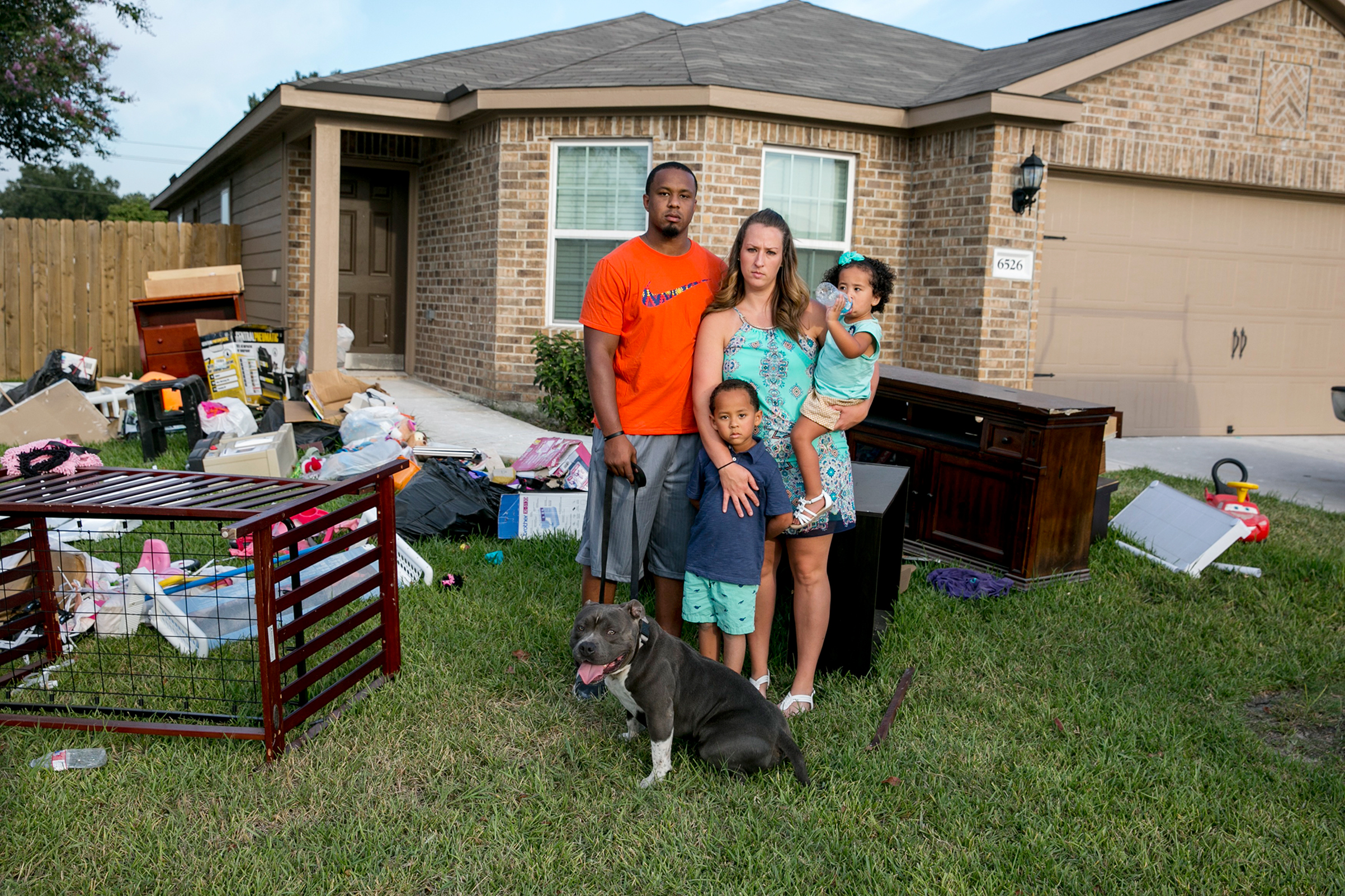 Isiah Courtney stands in the front yard of his Houston home with his wife, Danielle, son Bryson, daughter Aubree and dog Bruce (Ilana Panich-Linsman for TIME)
