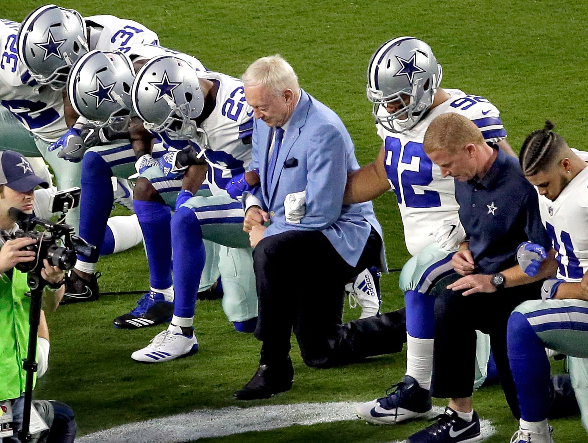 Jerry Jones owner of the Dallas Cowboys knees in unity