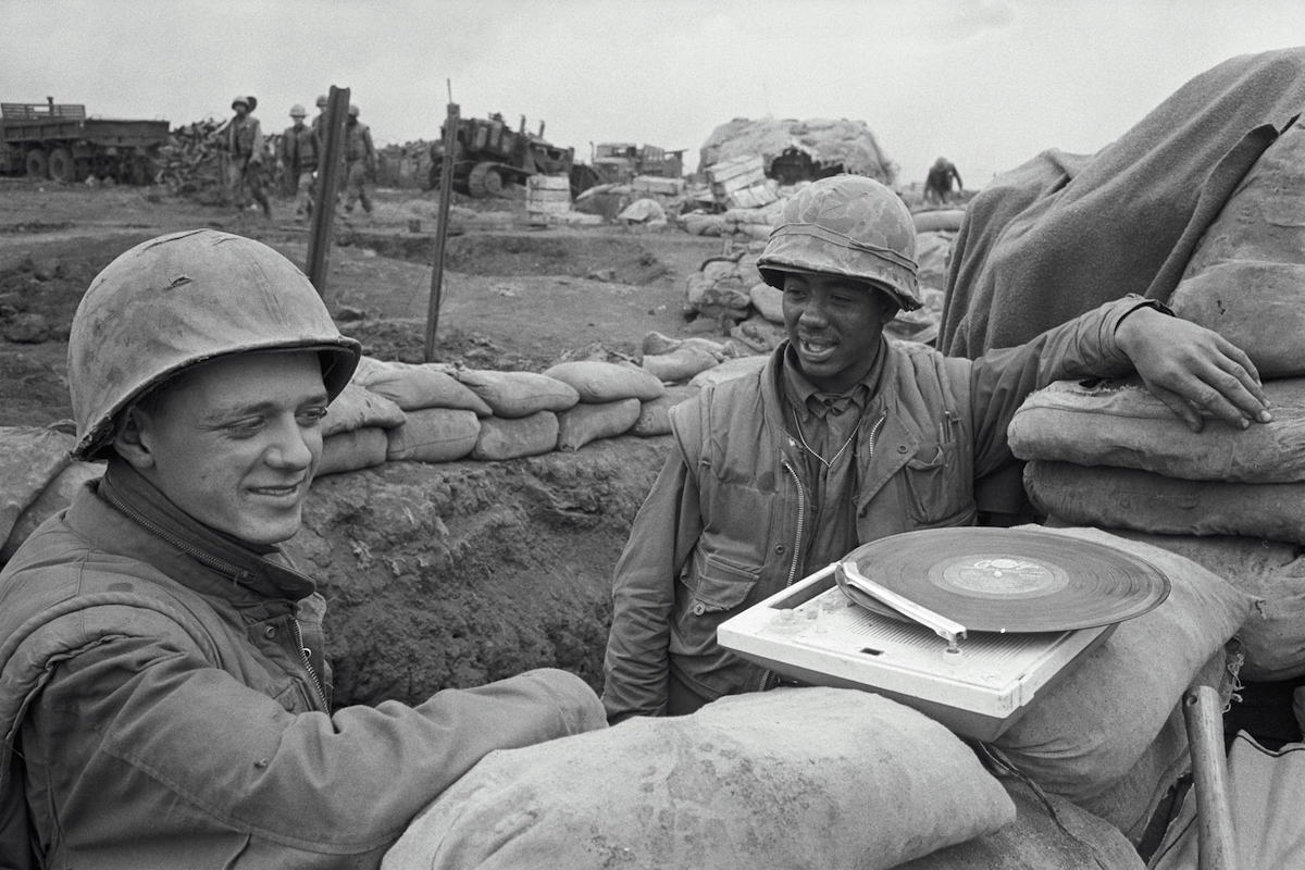 In Khe Sanh, South Vietnam, Pfc. Daniel Wolff (L) of Springfield, Mo., and Pfc. Johnny Harper of Macon, Ga., listen to a record player as they stand in a trench at the beleaguered U.S. Marine outpost in 1968. (Getty Images / Bettmann Archive)