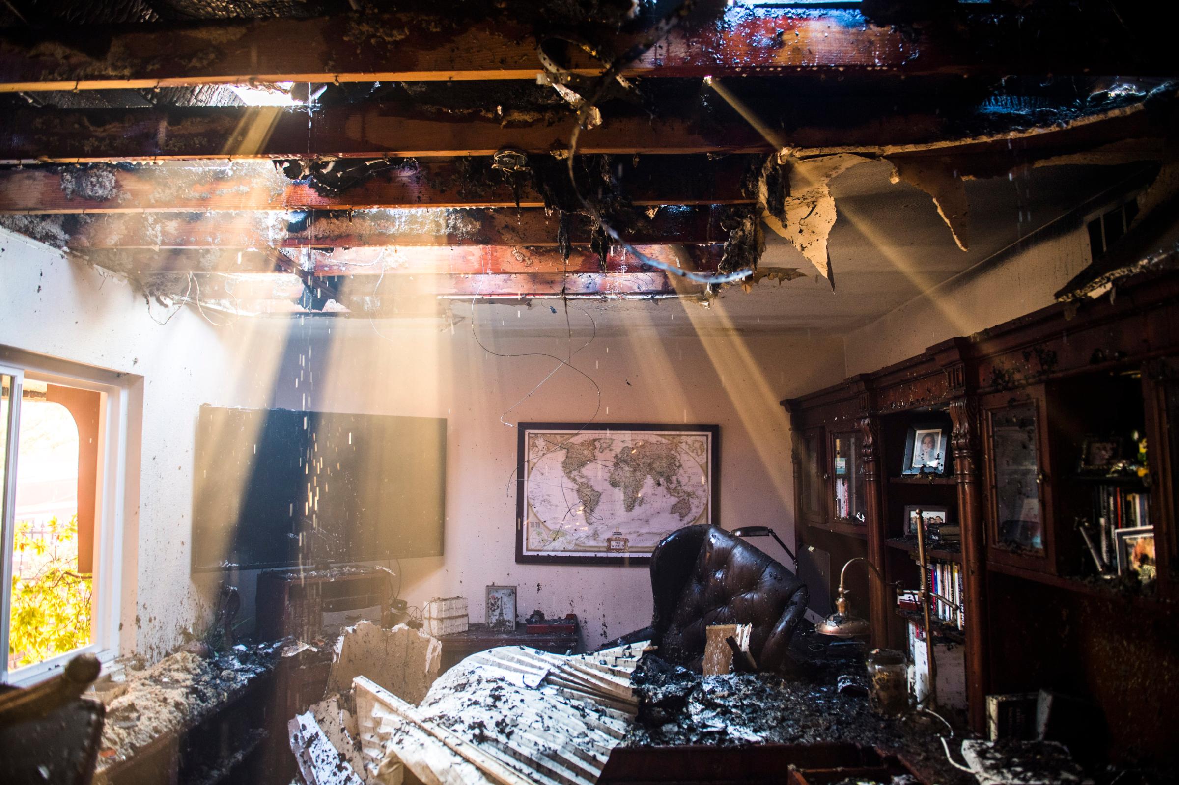 Smoke and water stream through the roof of a damaged home
