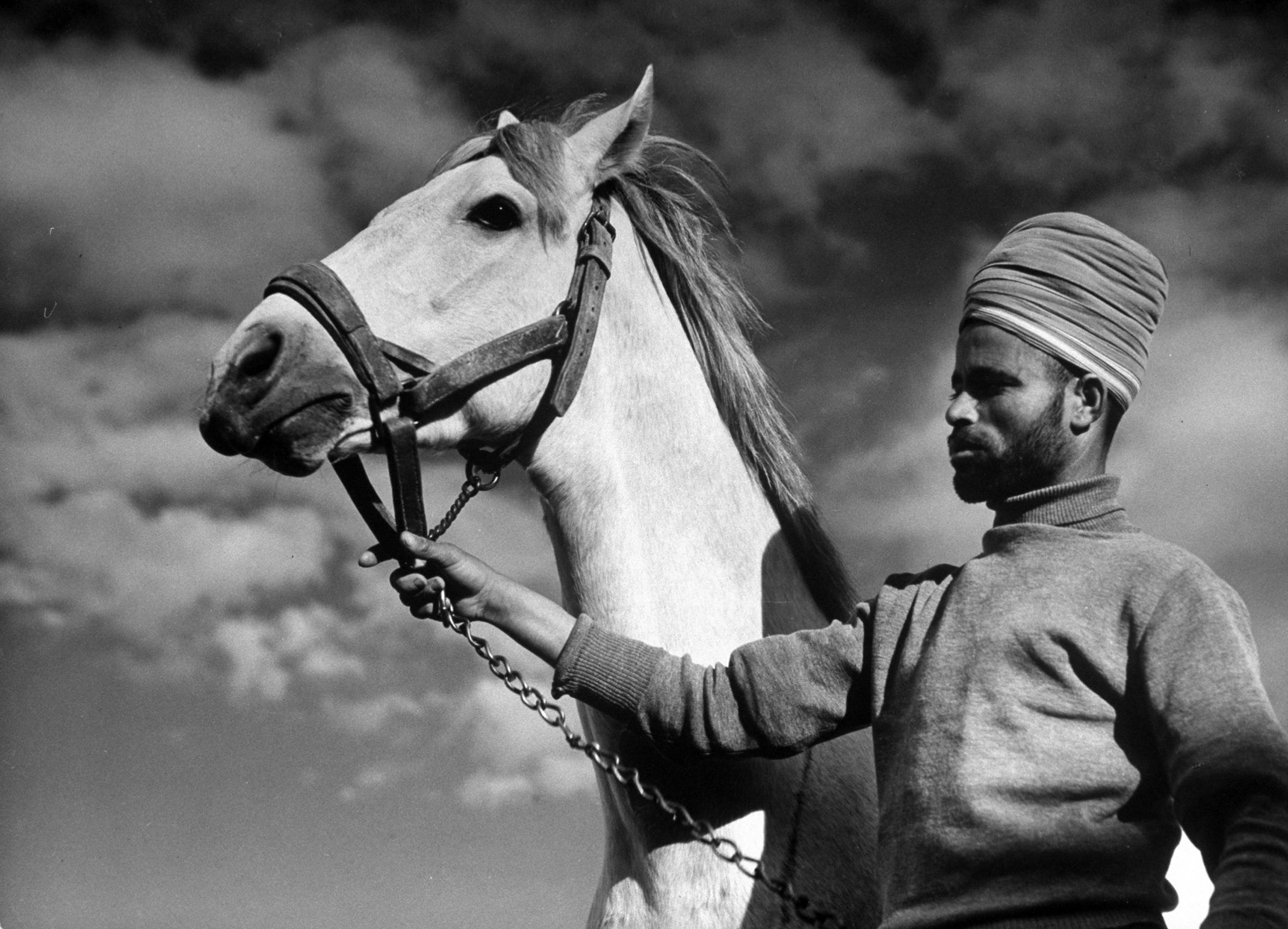 Moroccan soldier of the French expeditionary force, holding the General's Arabian horse, at garrison in the great citadel, 1940.