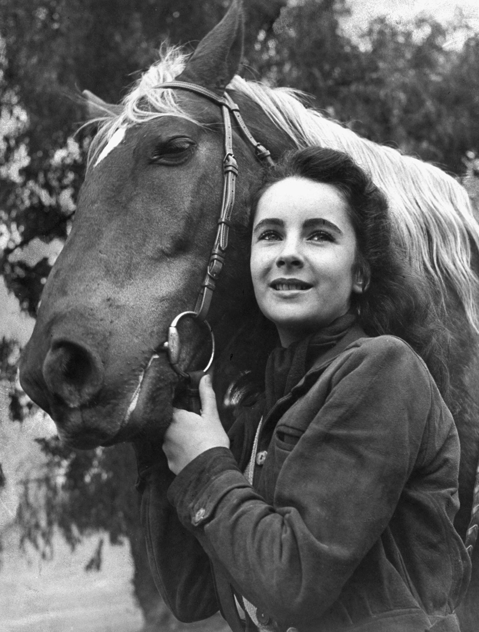 Elizabeth Taylor posing with saddle horse after her smash movie debut in "National Velvet," 1945.