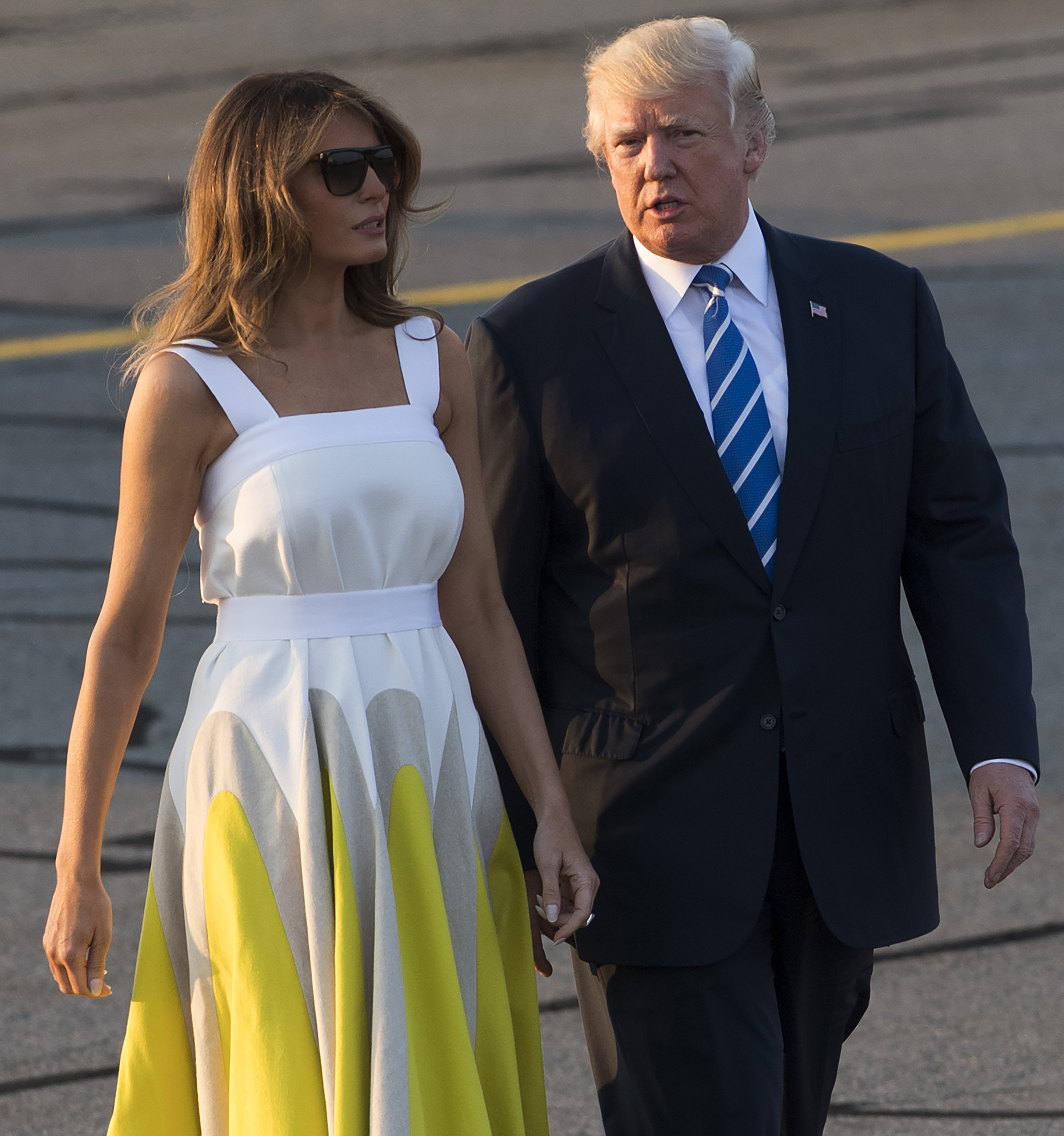 President Donald Trump and First lady Melania Trump, wearing a yellow and white Delpozo dress,  walk to board Air Force One prior to departure from Morristown Municipal Airport in New Jersey, Aug. 20, 2017.
