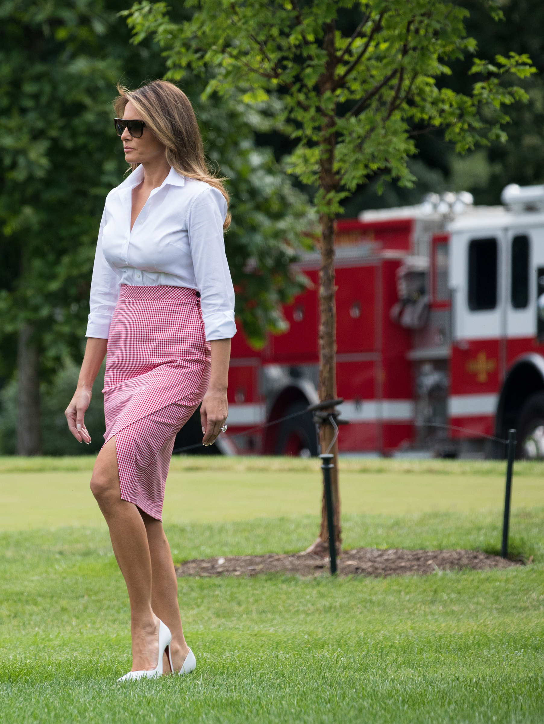 First lady Melania Trump wearing a gingham wrap-effect skirt by Altuzarra and a white top, walks with her husband President Donald and their son Barron on the South Lawn of the White House in Washington, D.C., before their departure to Camp David, June 17, 2017.
