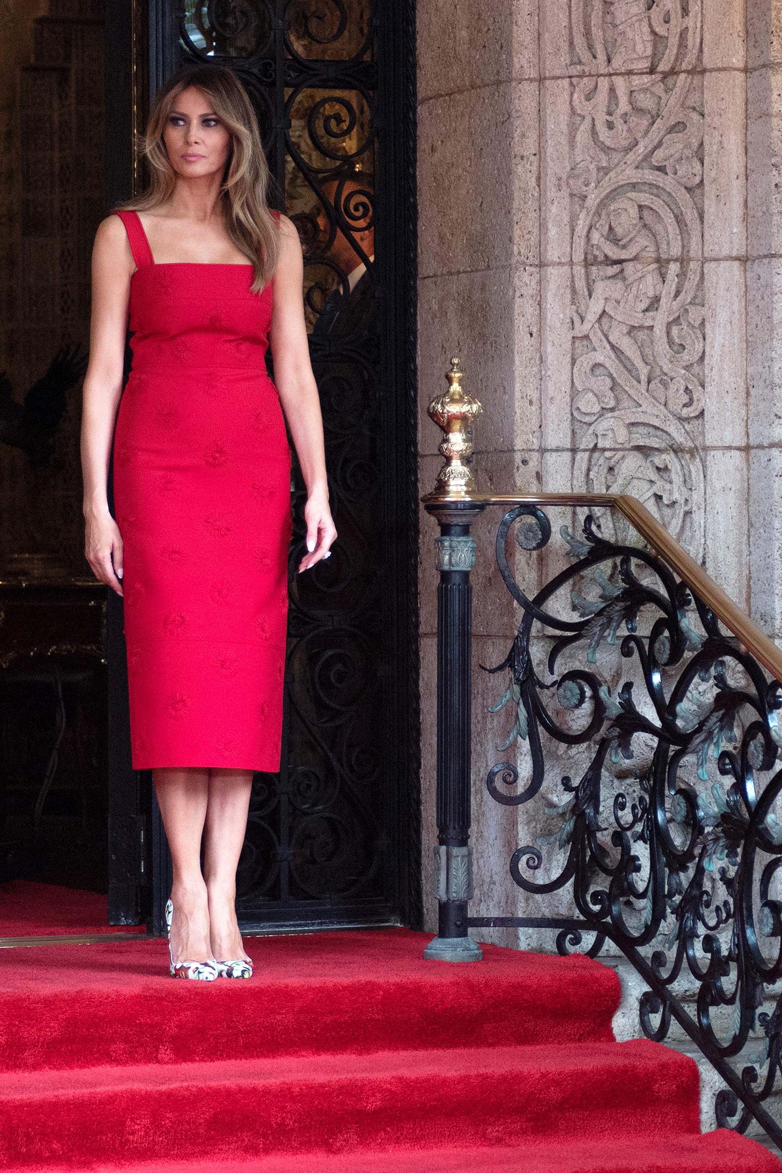 First lady Melania Trump wears a sleeveless red daisy-appliqué crepe midi dress by Valentino, awaits the arrival of Chinese President Xi Jinping and his wife Peng Liyuan at the Mar-a-Lago estate in West Palm Beach, Florida, on April 6, 2017.