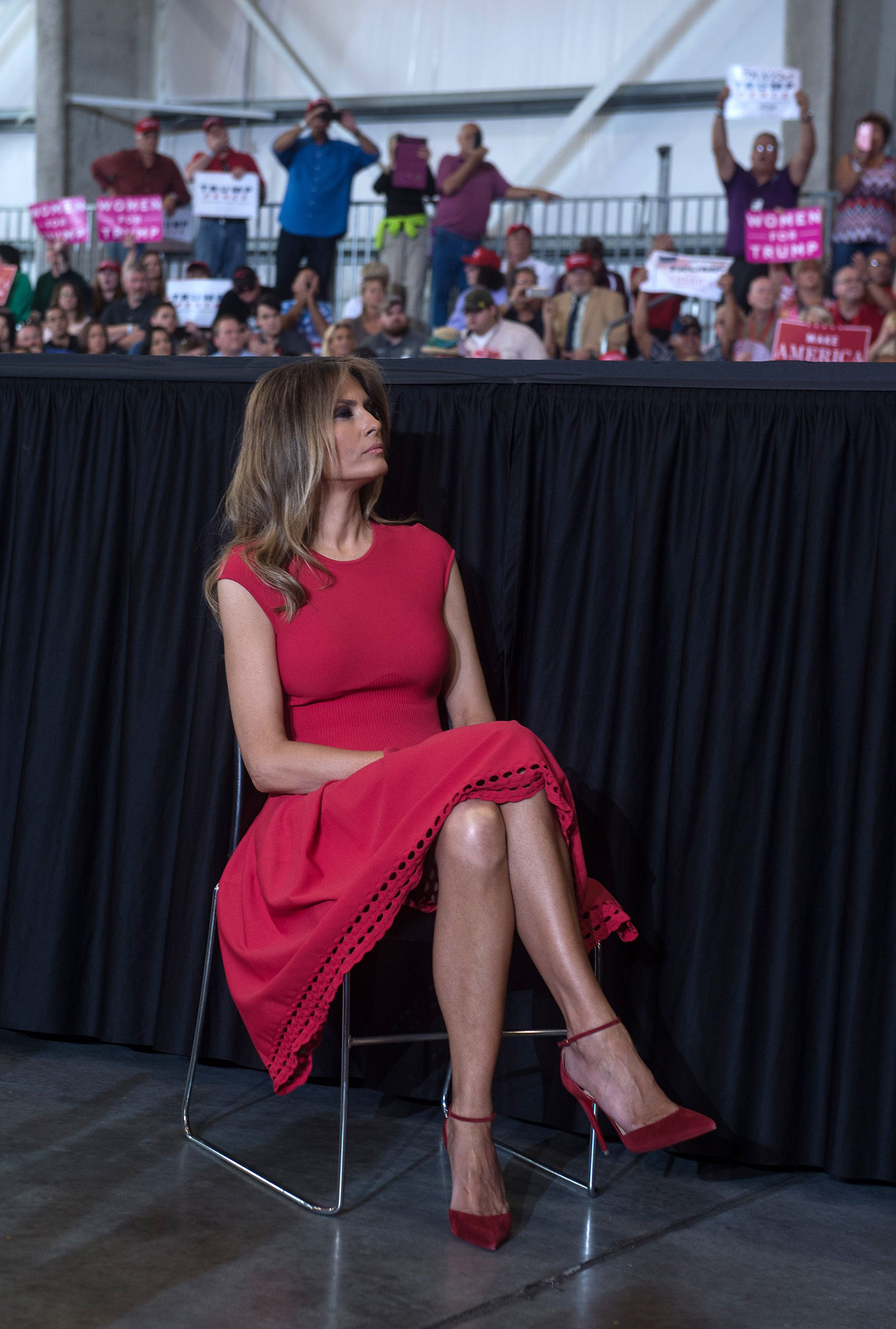 US First Lady Melania Trump wearing an Alexander McQueen red dress, listens as her husband, US President Donald Trump addresses a rally in Melbourne, Fla., on Feb.18, 2017