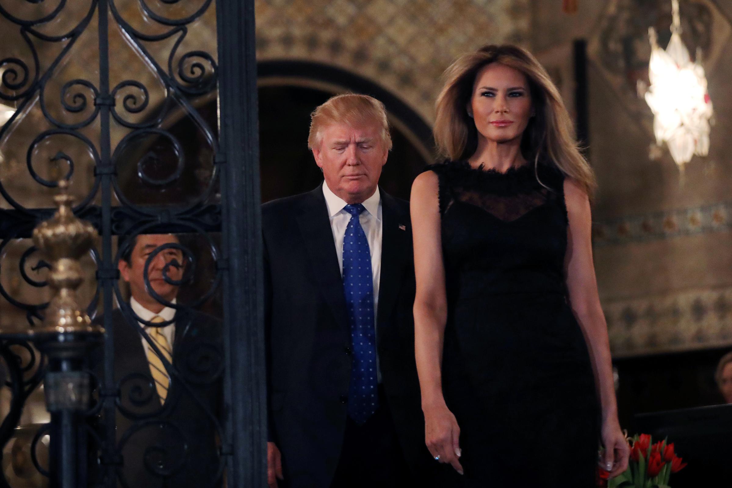 President Donald Trump with First Lady Melania wearing a sleeveless black dress with a low-dipping back and a layer of lace on top, walk to pose for a photograph with Japanese Prime Minister Shinzo Abe before attending dinner at Mar-a-Lago Club in Palm Beach, Fla., Feb. 11, 2017. a photograph before attending dinner at Mar-a-Lago Club in Palm Beach, Florida, U.S.