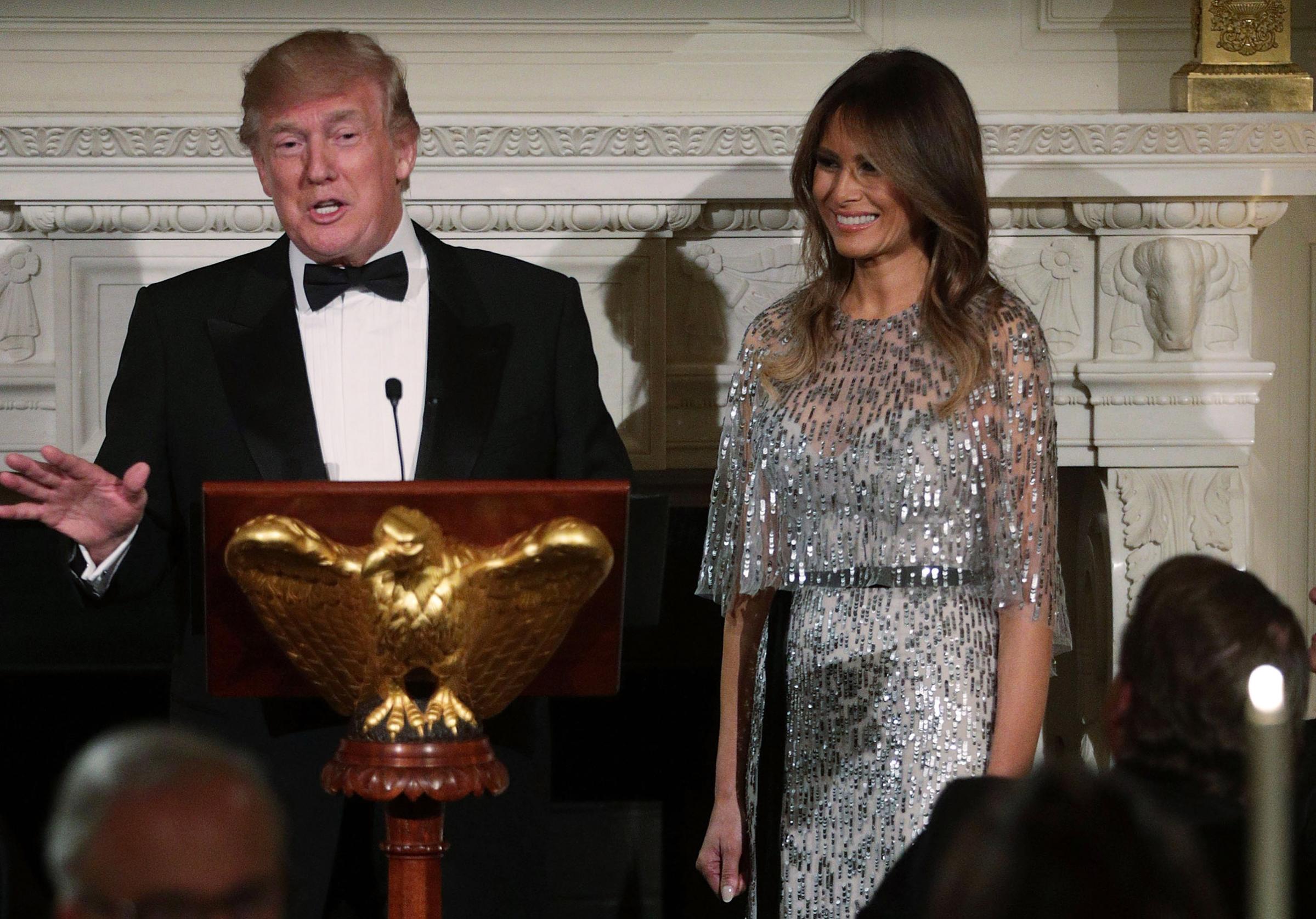 President Donald Trump speaks with first lady Melania Trump at his side, wearing a Monique Lhuillier silver dress stands, during a reception at the State Dining Room of the White House Sept.14, 2017, in Washington, DC. President Donald Trump speaks as first lady Melania Trump wearing a Monique Lhuillier silver dress listens during a reception at the State Dining Room of the White House Sept.14, 2017, in Washington, DC.