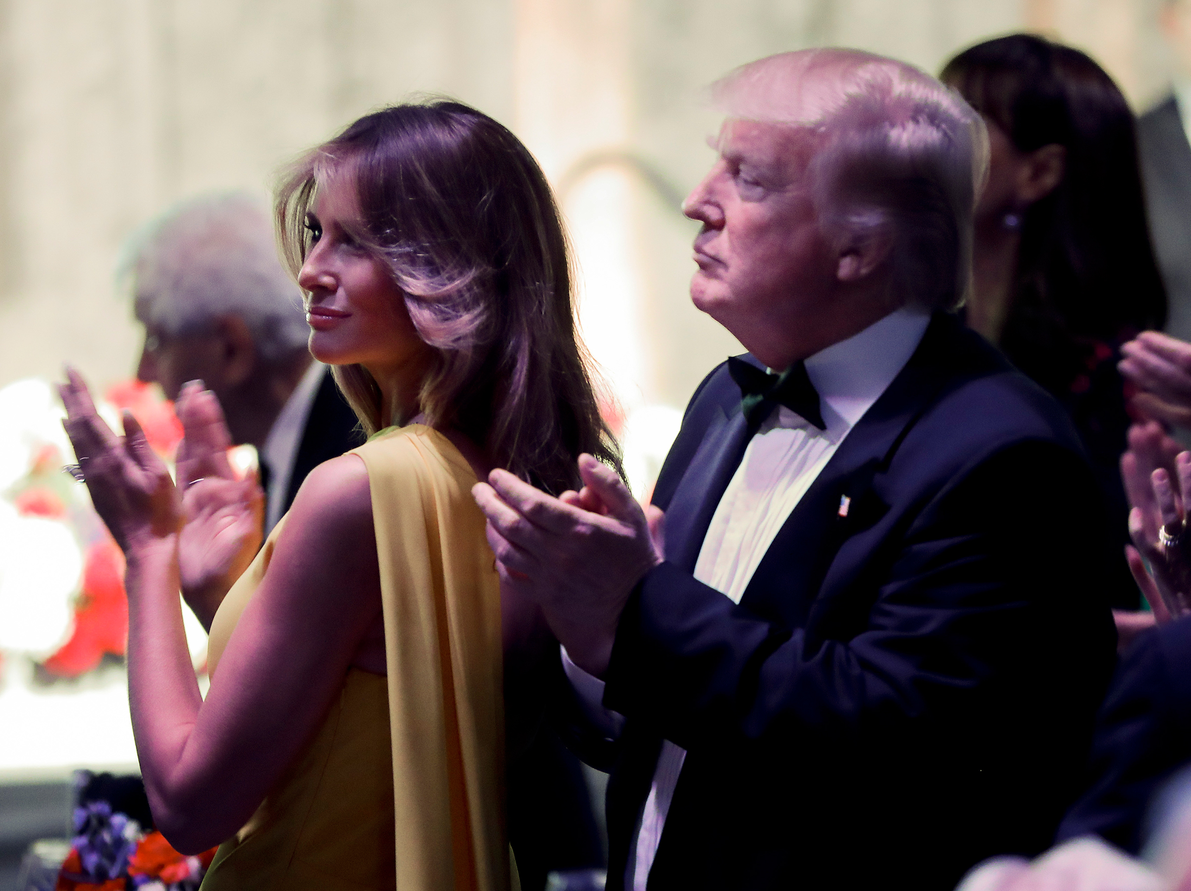 President Trump and first lady Melania Trump wearing yellow Dior gown applaud at dinner with Australian Prime Minister Malcolm Turnbull aboard the USS Intrepid, in New York CIty, May 4, 2017.