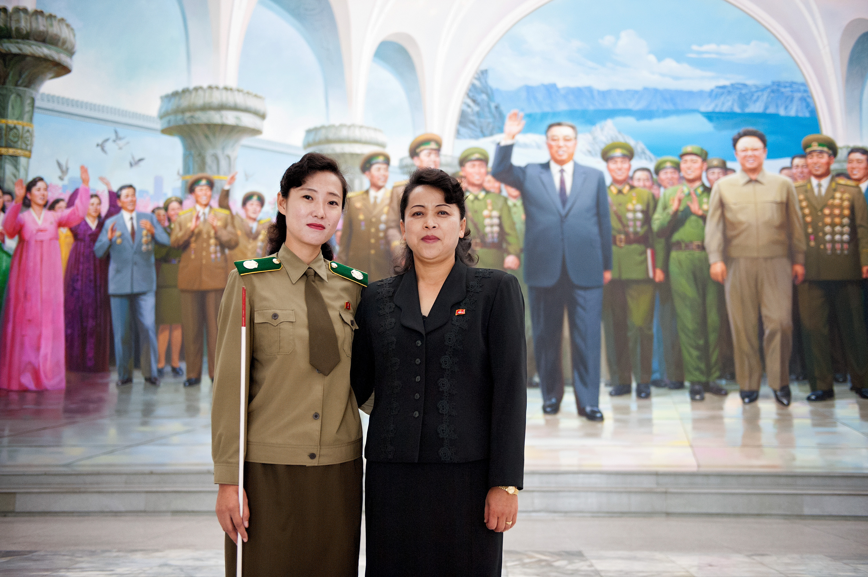 Two local guides pose in front of a mural in Pyongyang. (Werner Kranwetvogel)