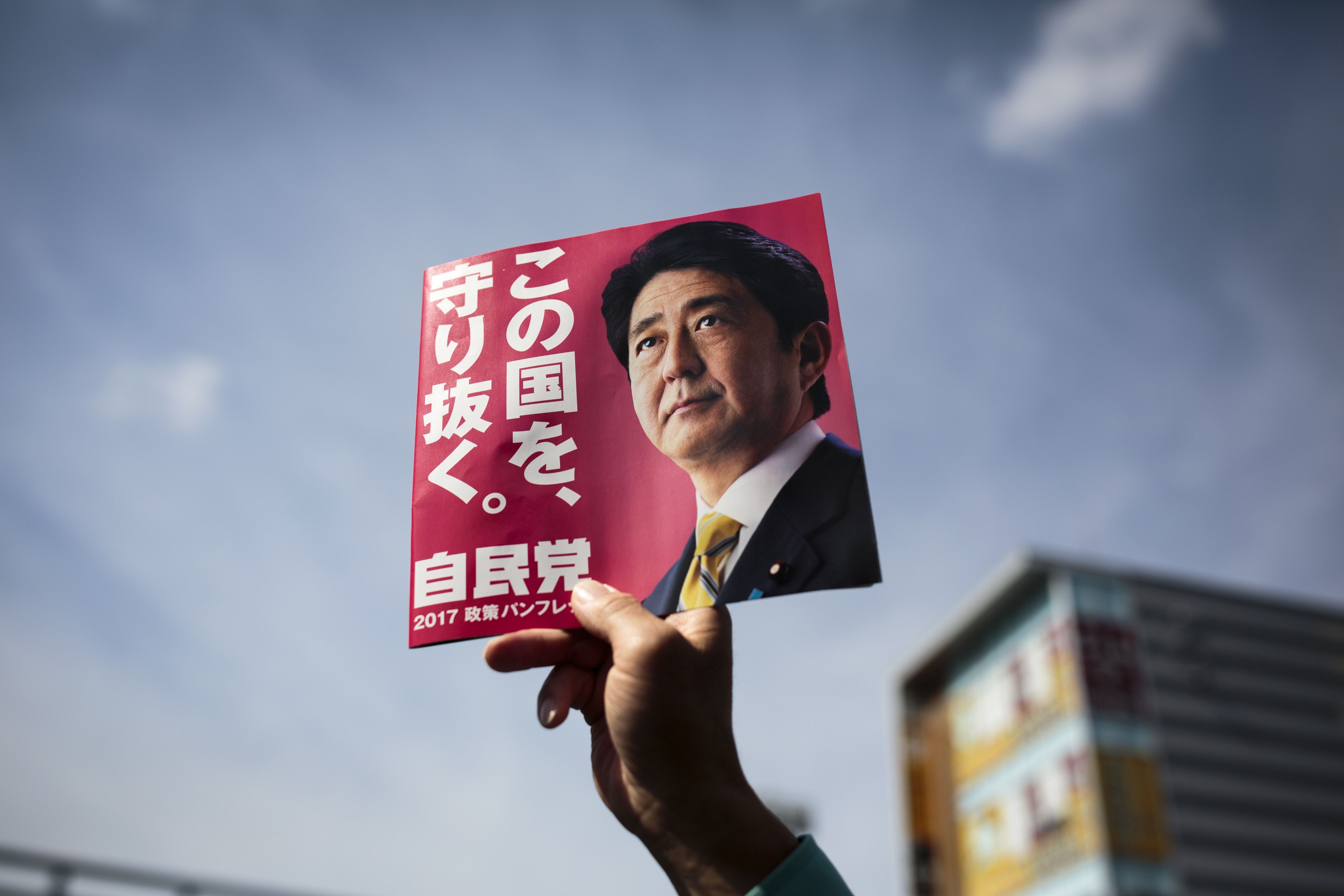 In this picture taken on October 18, 2017, a man holds an electoral leaflet showing Japan's Prime Minister and ruling Liberal Democratic Party (LDP) president Shinzo Abe during an election campaign in Saitama. (BEHROUZ MEHRI—AFP/Getty Images)