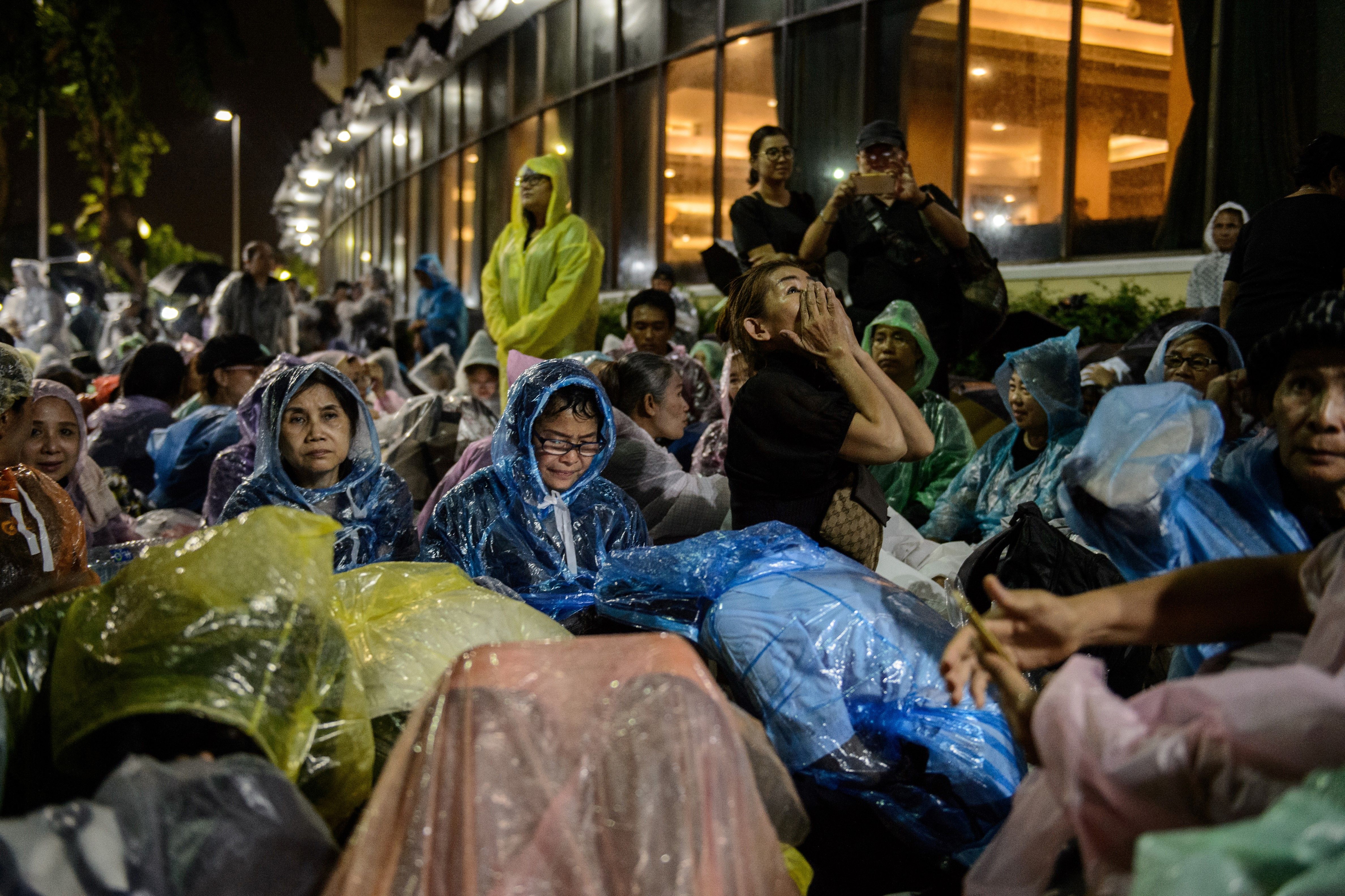 Mourners shelter from the rain while waiting for the funeral of the late Thai King Bhumibol Adulyadej in Bangkok on Oct. 24, 2017. (Anthony Wallace—AFP/Getty Images)