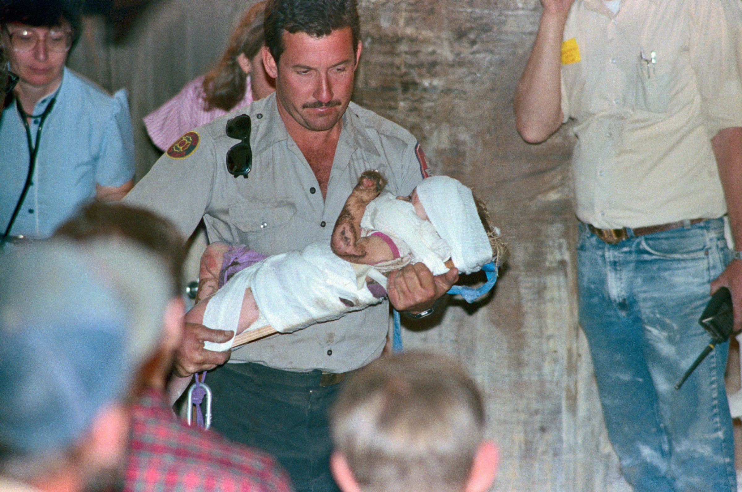 Rescuer rushes baby rescued from fall into a well where lay for three days before she was rescued, Oct. 16, 1987.