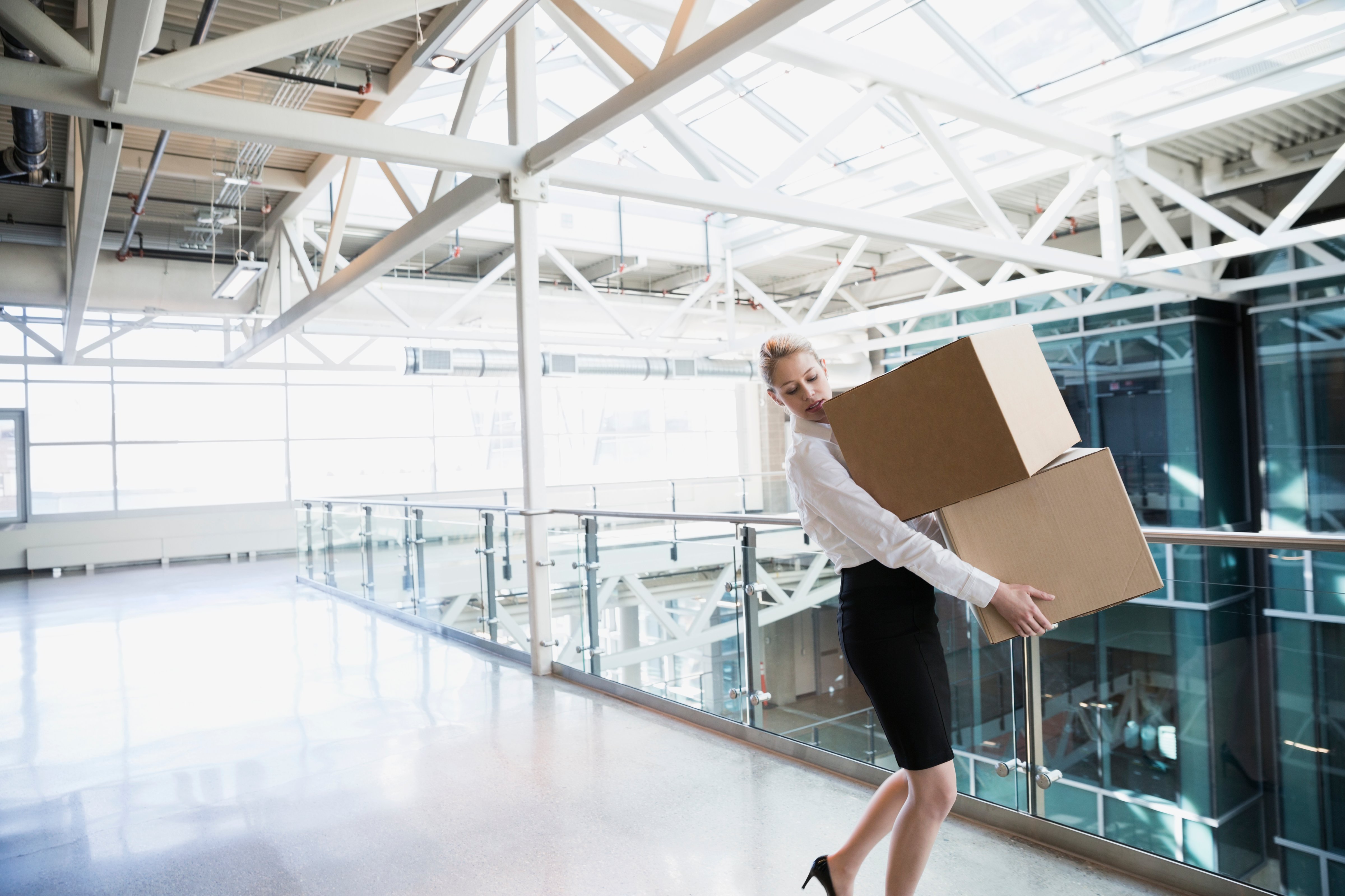 Businesswoman carrying cardboard boxes in atrium