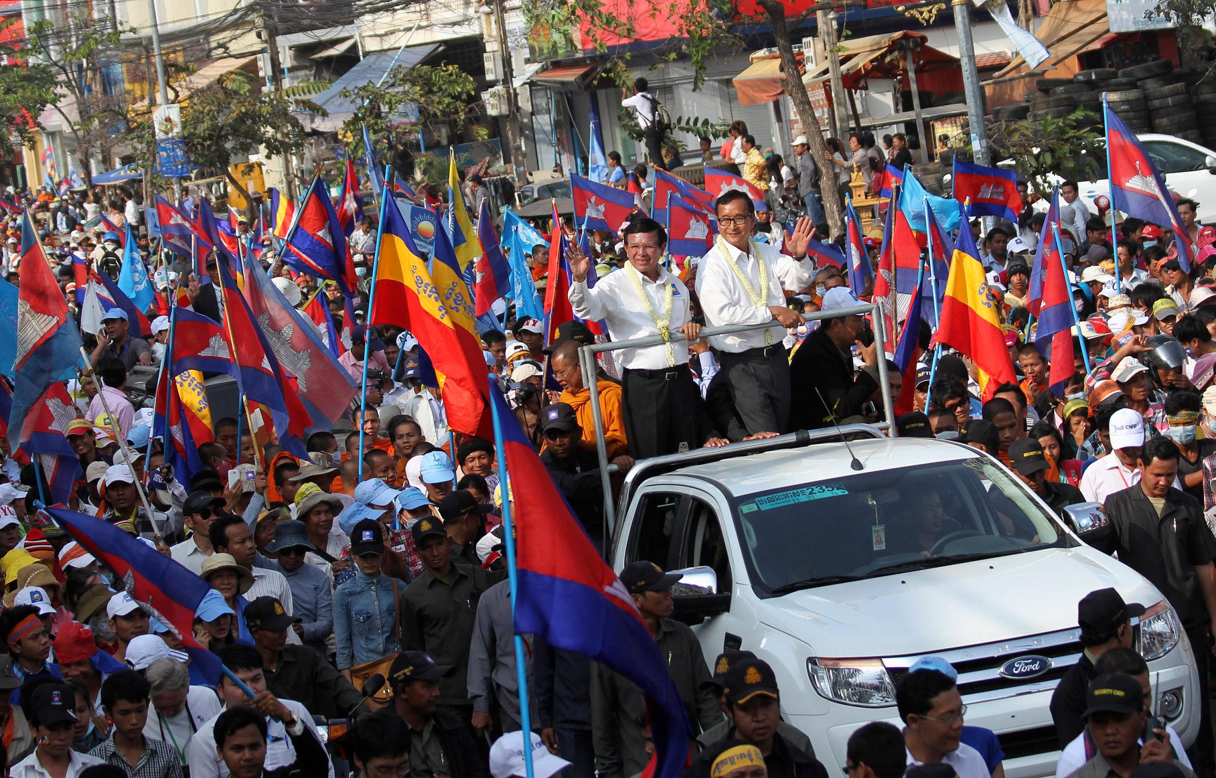 Sam Rainsy, president of the opposition Cambodian National Rescue Party and party vice-president Sokha, stand on a vehicle while greeting supporters during a protest in Phnom Penh