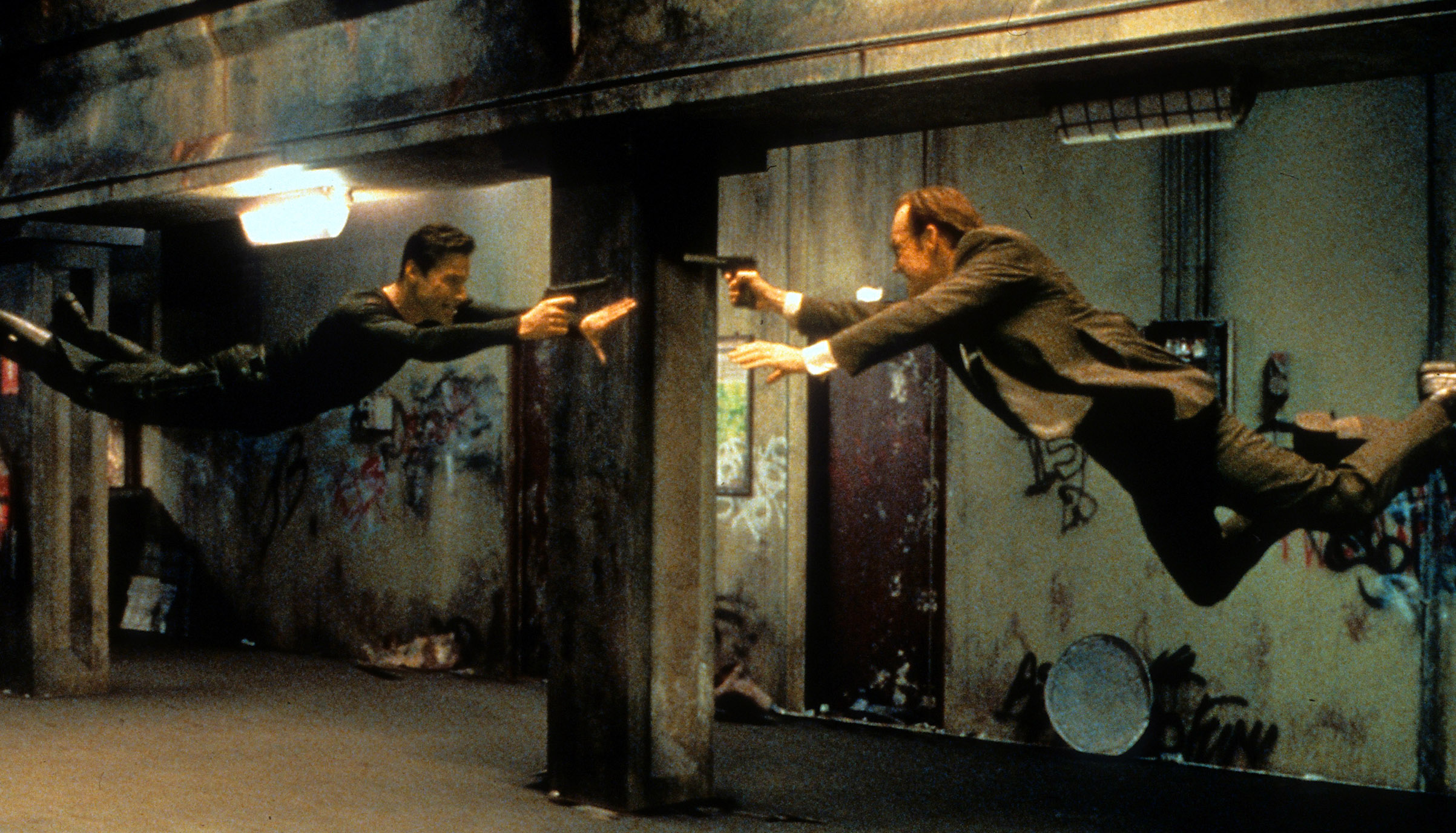 Keanu Reeves and Hugo Weaving pointing guns at each other in a scene from the film 'The Matrix', 1999. (Warner Brothers/Getty Images)