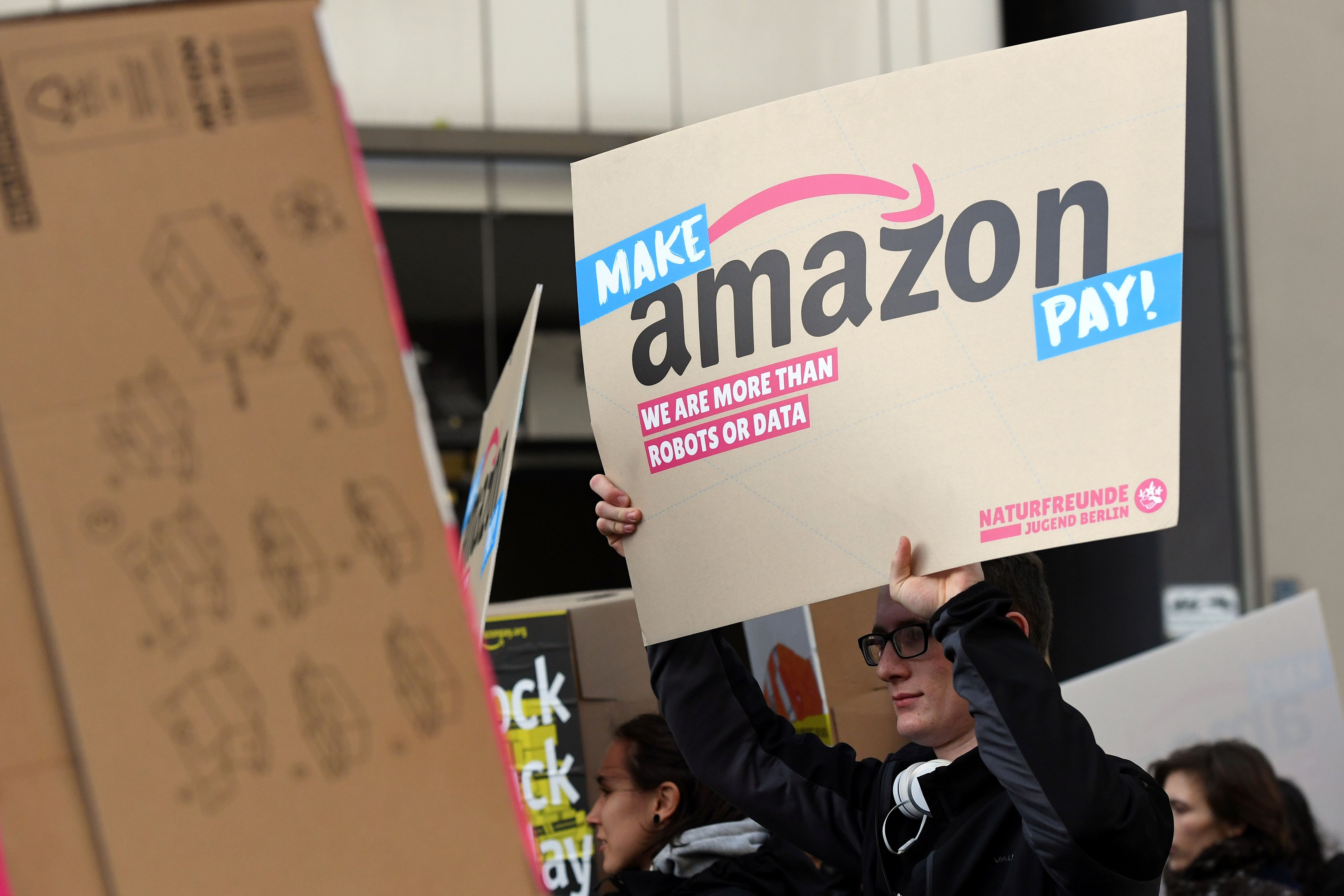 A protester holds a placard during a demonstration to ask the online retailer Amazon on November 24, 2017 on the 
