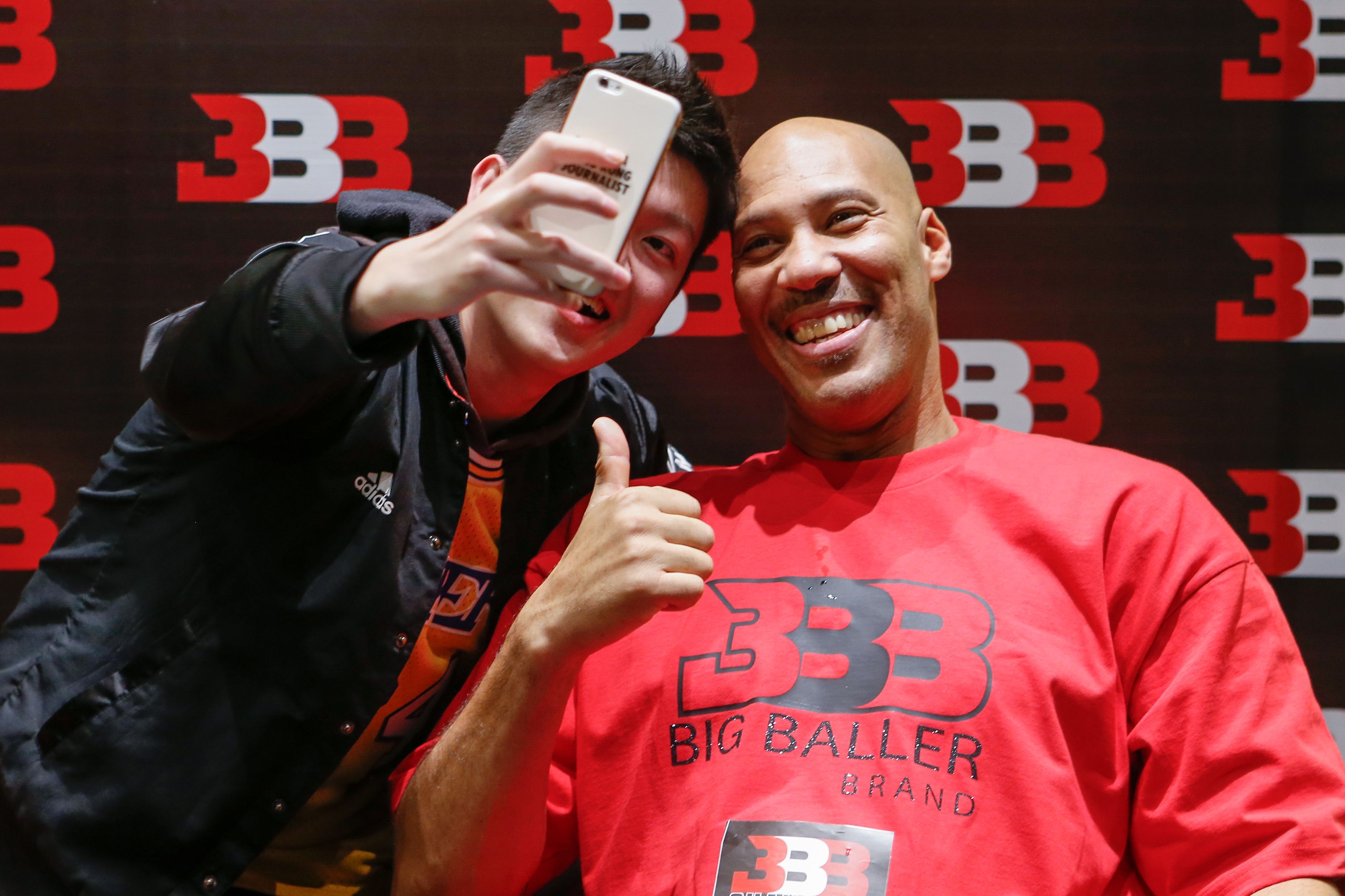 LaVar Ball (R), father of LiAngelo Ball and the owner of the Big Baller brand, poses for a selfie with a fan during a promotional event in Shanghai on November 10, 2017. LiAngelo Ball, the younger brother of Los Angeles Lakers star Lonzo Ball, was among three college basketball players arrested in China on suspicion of shoplifting, US media reports said on November 8. (STR&mdash;AFP/Getty Images)