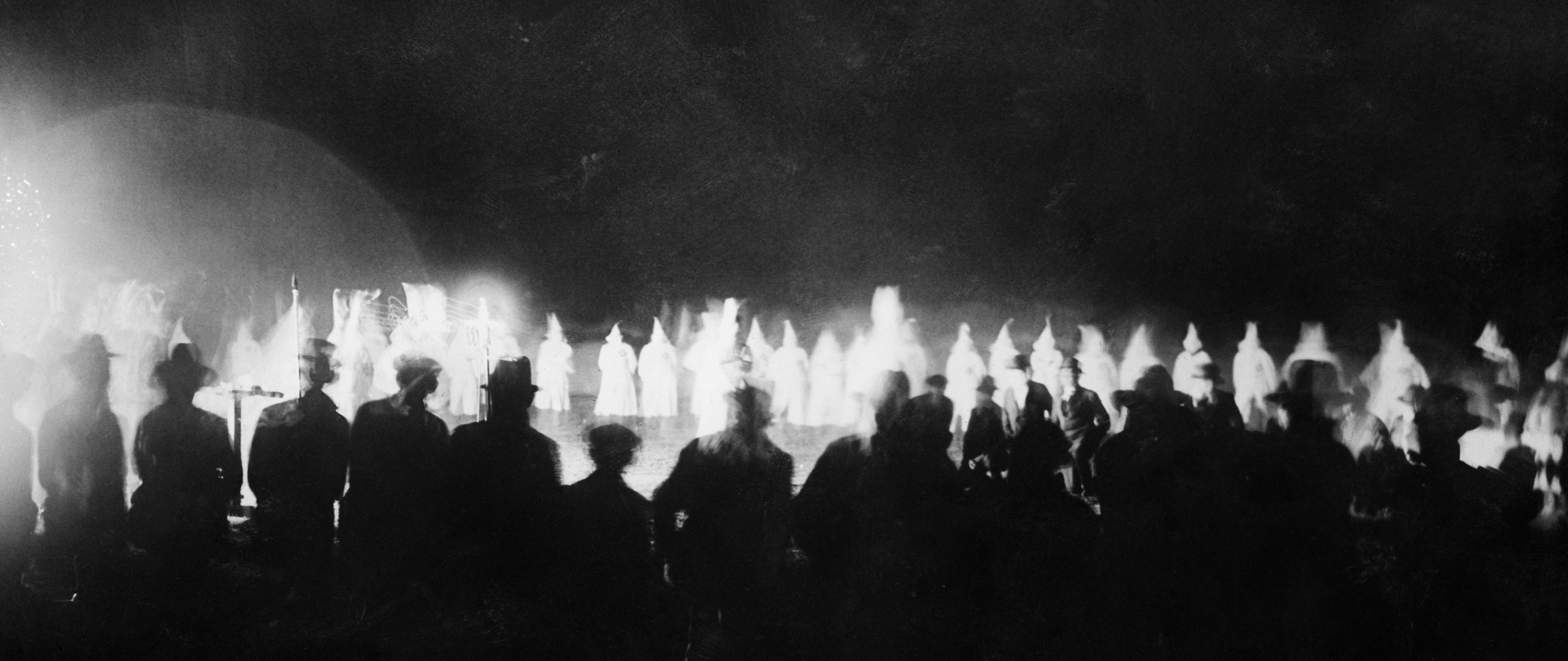 Onlookers watch as the Ku Klux Klan initiates new members at a Miami golf course in the 1920s. (Bettmann / Getty Images)